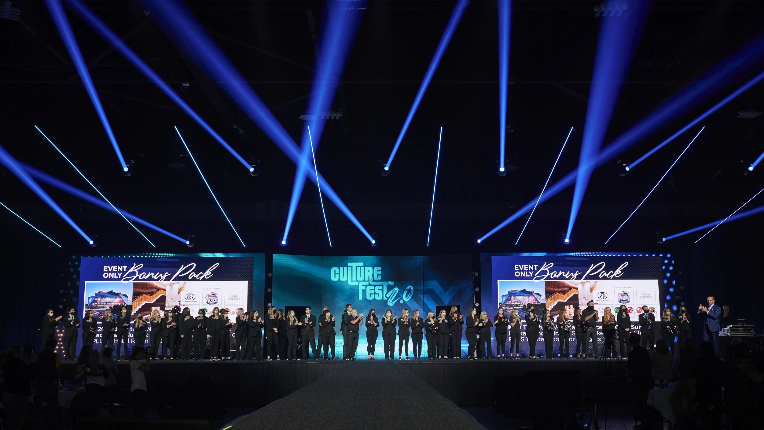 Wide-angle corporate event photography featuring a large group onstage beneath dramatic blue lighting at an Atlanta conference.