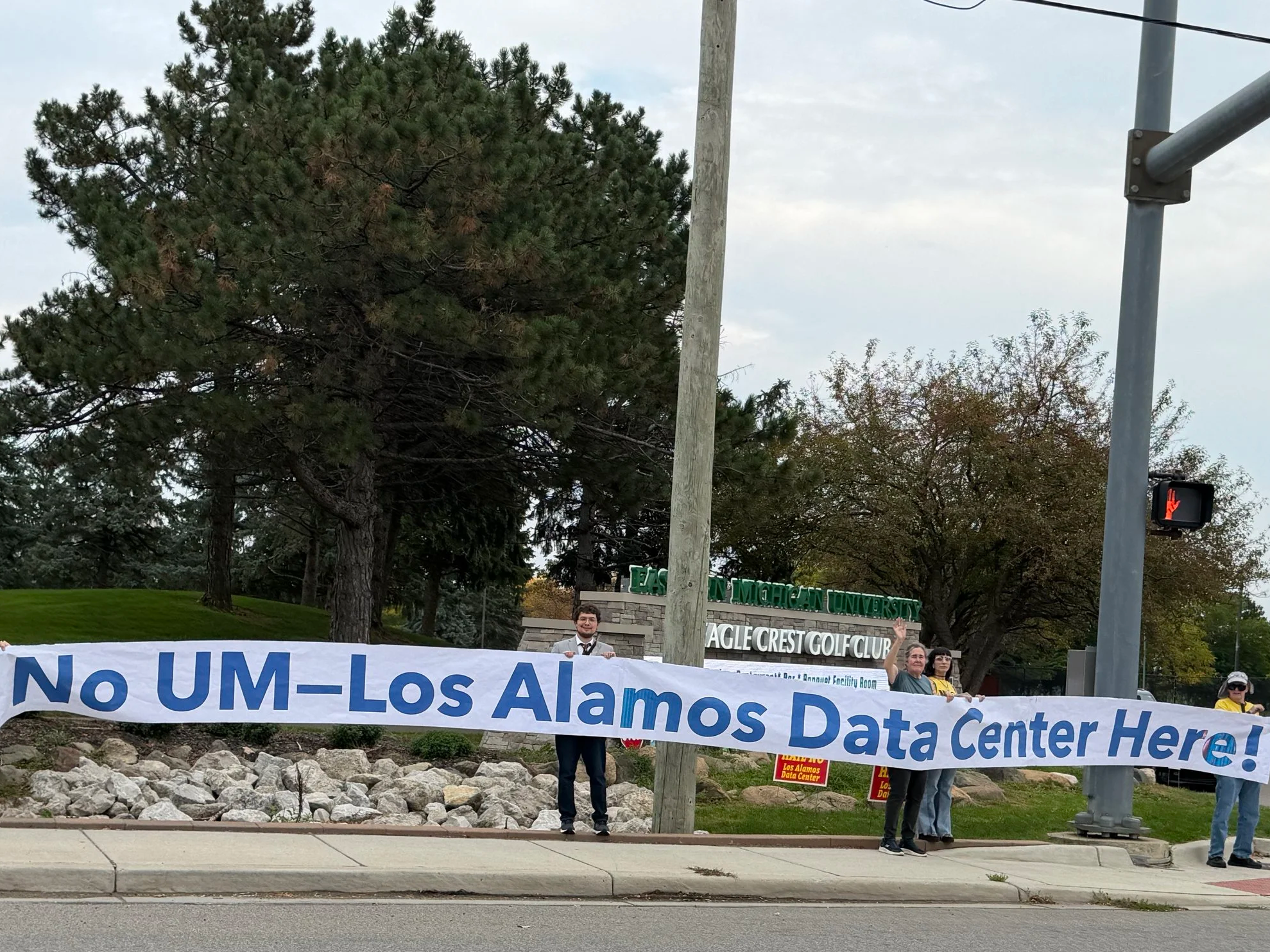 Banner held up by protestors in blue block letters says "No UM-Los Alamos Data Center Here!"