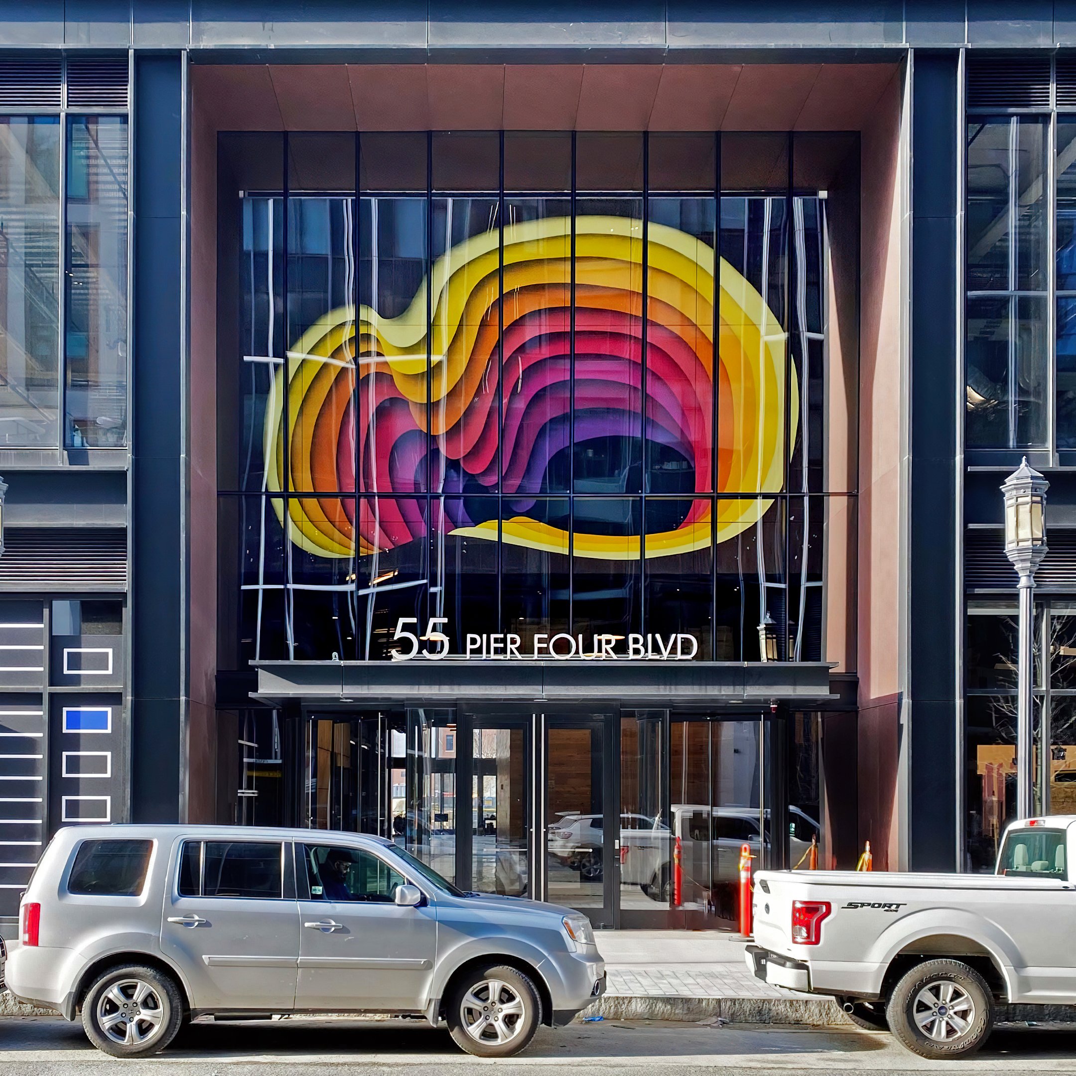 A full-view of a three-dimensional mural by artist 1010 in front of the Boston Amazon headquarters.