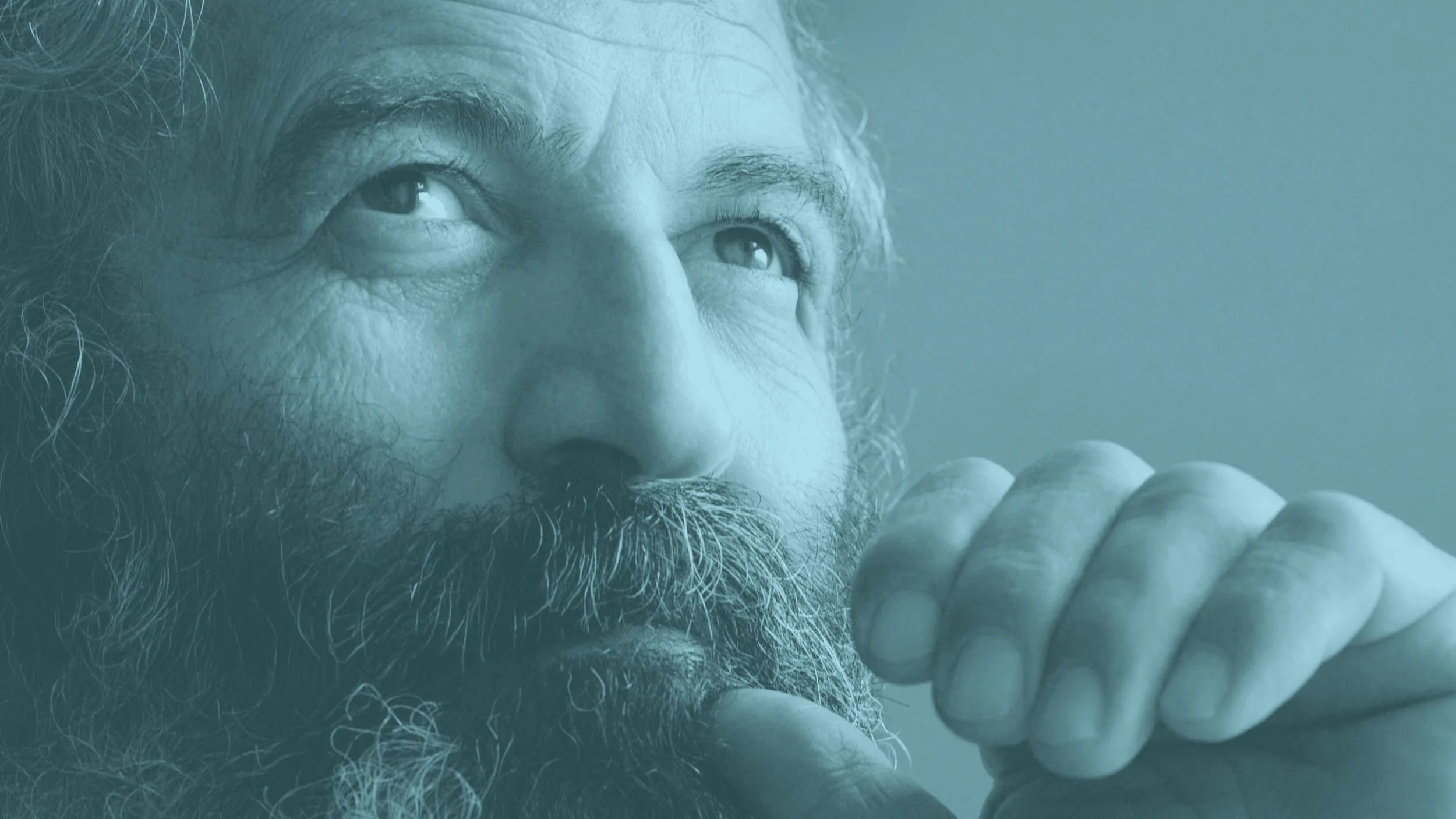 Older man with long white hair and facial hair looking hopefully upwards