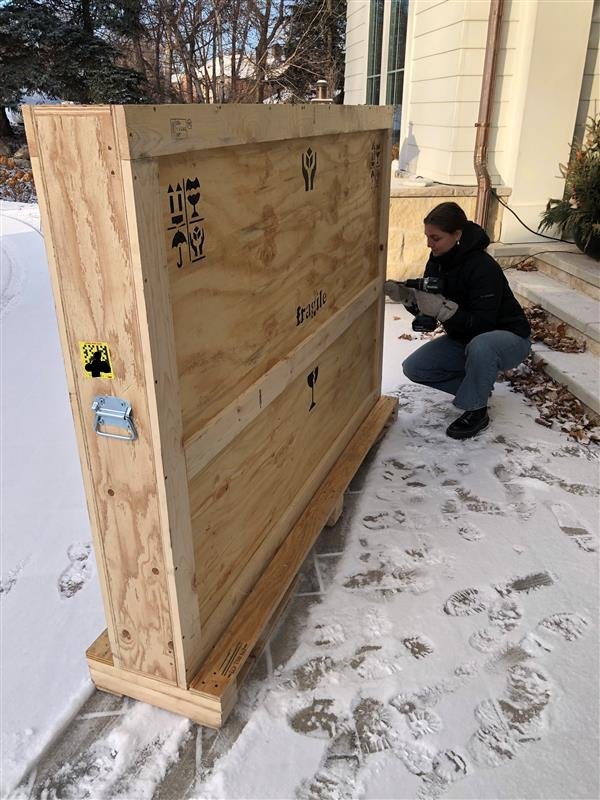 Art handler opening crated artwork at a residence before installation