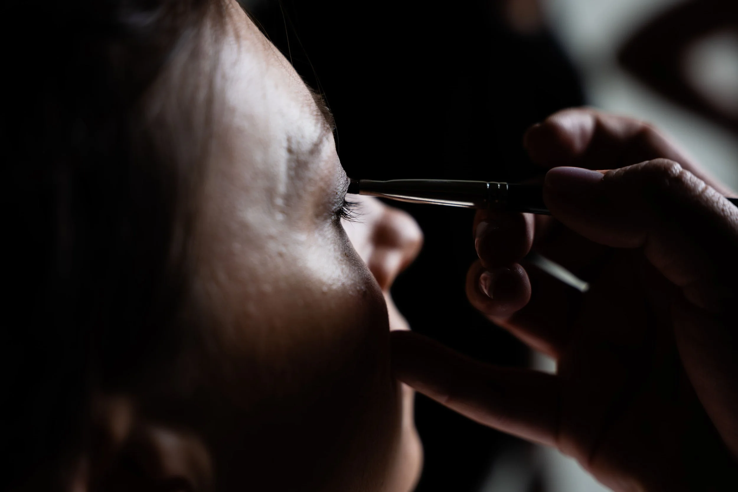 Un primo piano di una persona che sta applicando del trucco sugli occhi con un pennello.