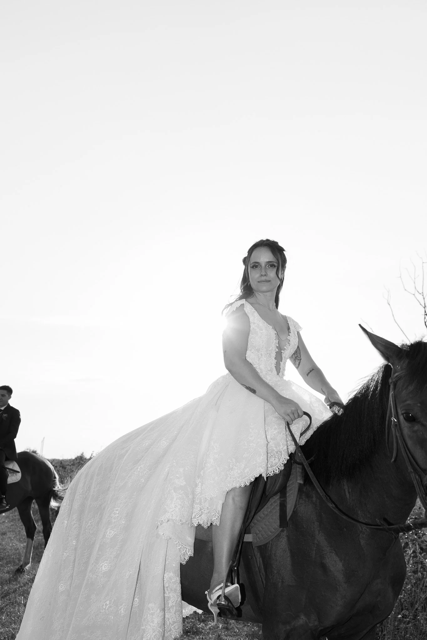 Una donna con un abito bianco da sposa su un cavallo all'aperto, maneggio di Marina Romea a Ravenna.