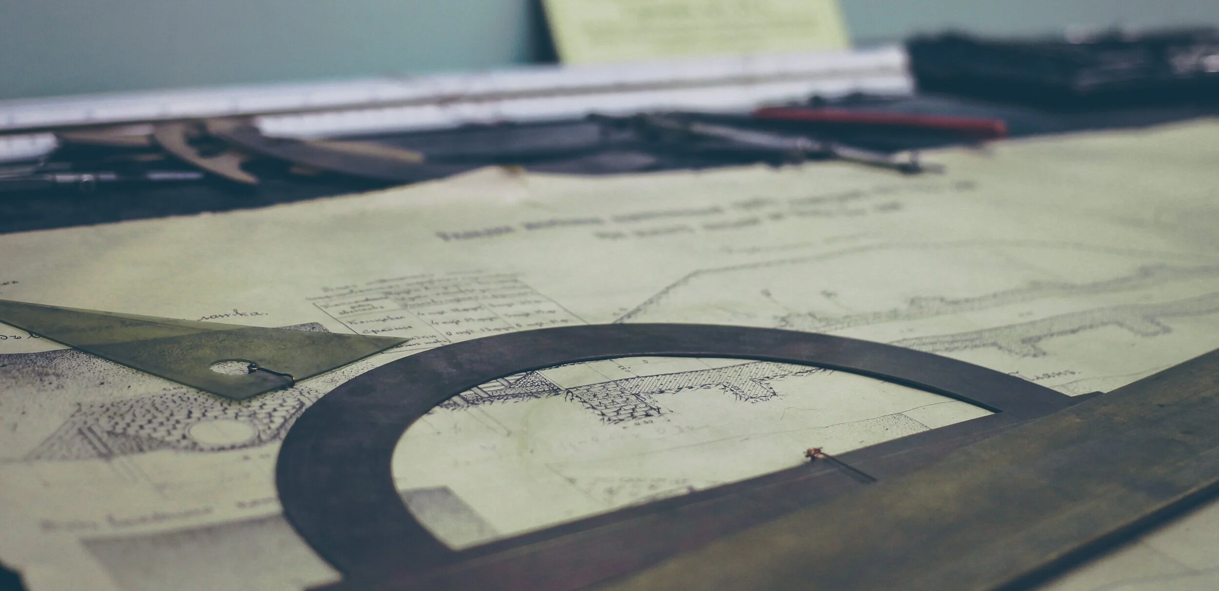 Μοιρογνωμόνιο, χάρακα και τετράγωνο κάθισμα πάνω από τεχνικά σχέδια.