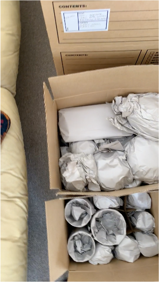 Cardboard boxes with wrapped items for moving or storage.