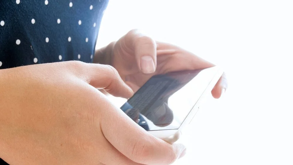 Adolescent girl's hands holding iphone