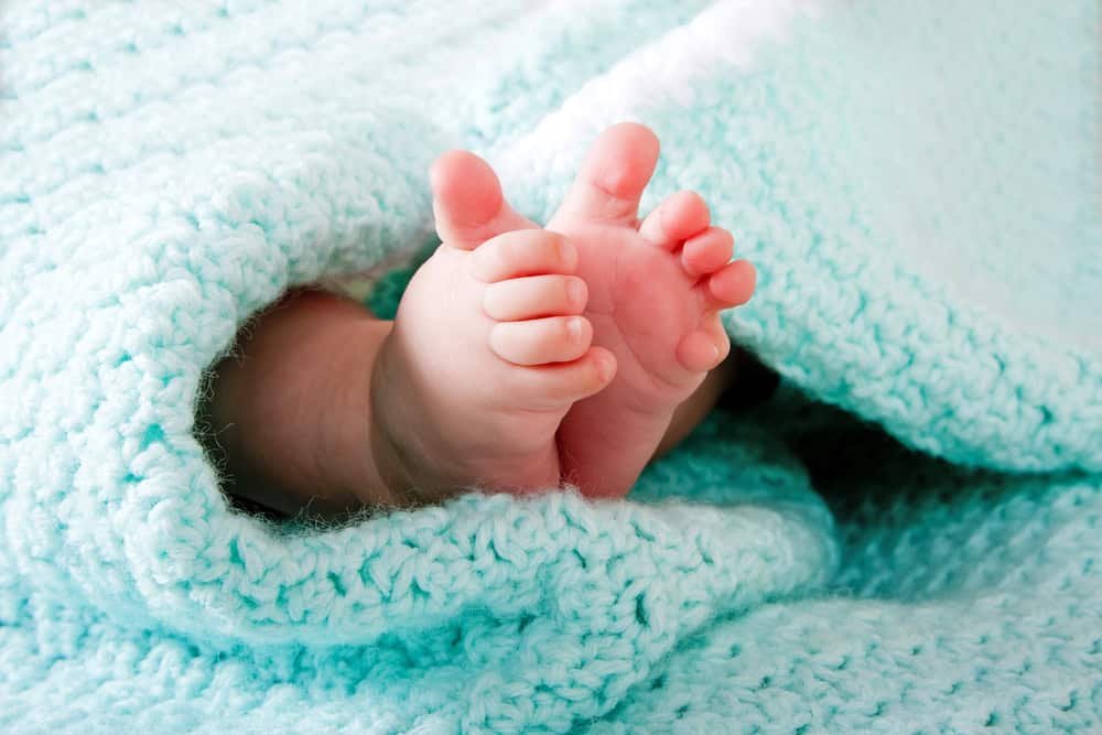 Infant feet wrapped in aqua coverlet