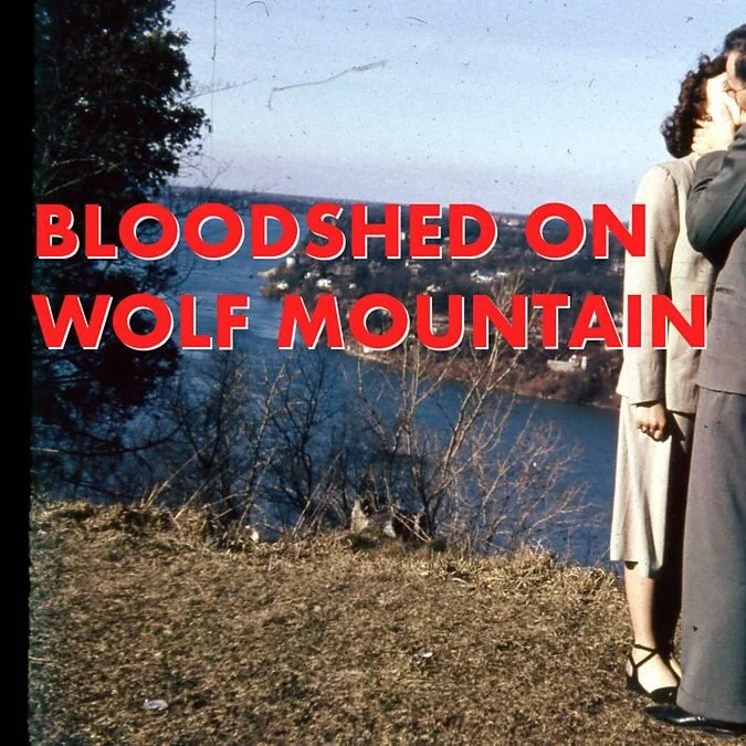 Vintage photograph of a couple standing near a scenic overlook with text "Bloodshed on Wolf Mountain" overlaying the image.