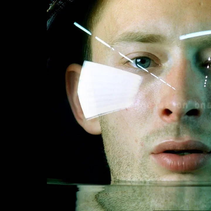 Close-up of a person's face partially submerged in water with reflections creating abstract patterns.
