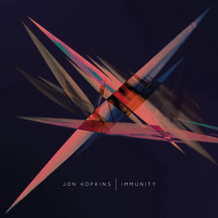 Abstract geometric artwork on dark background, featuring crisscrossing translucent, colorful spikes. Text reads "Jon Hopkins Immunity."