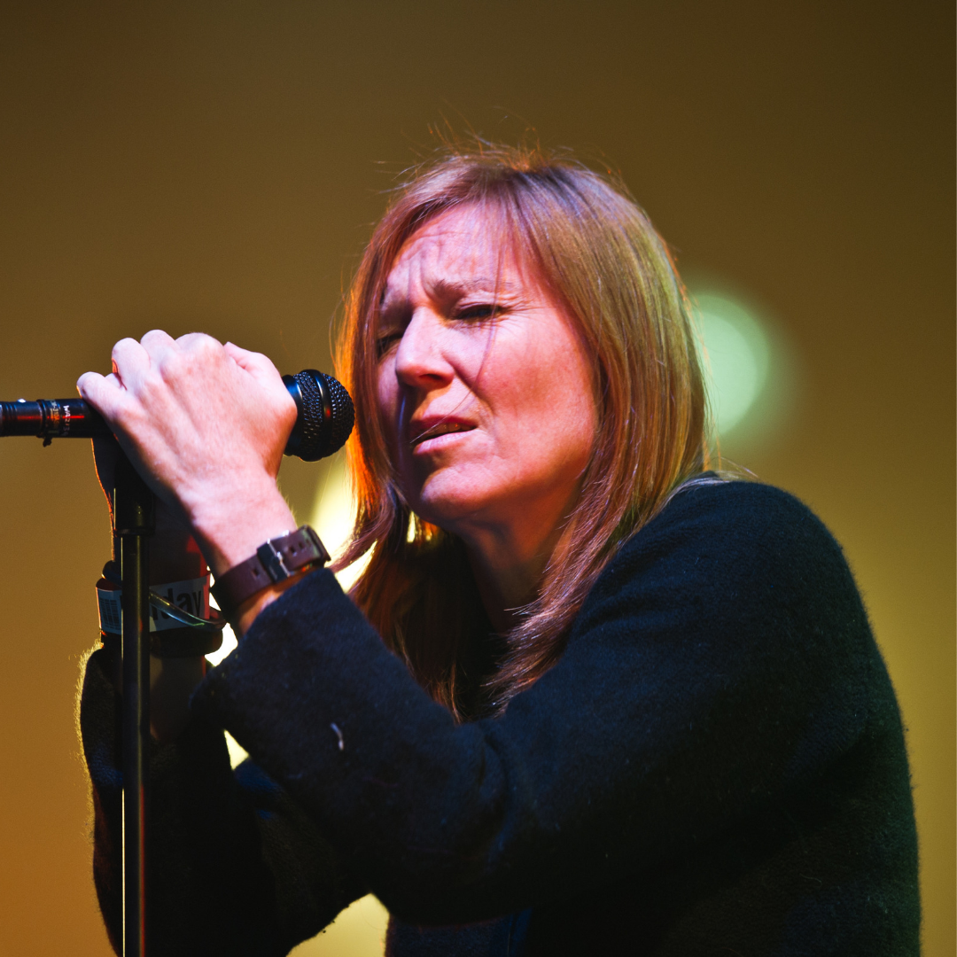 A person singing into a microphone on stage during a performance.