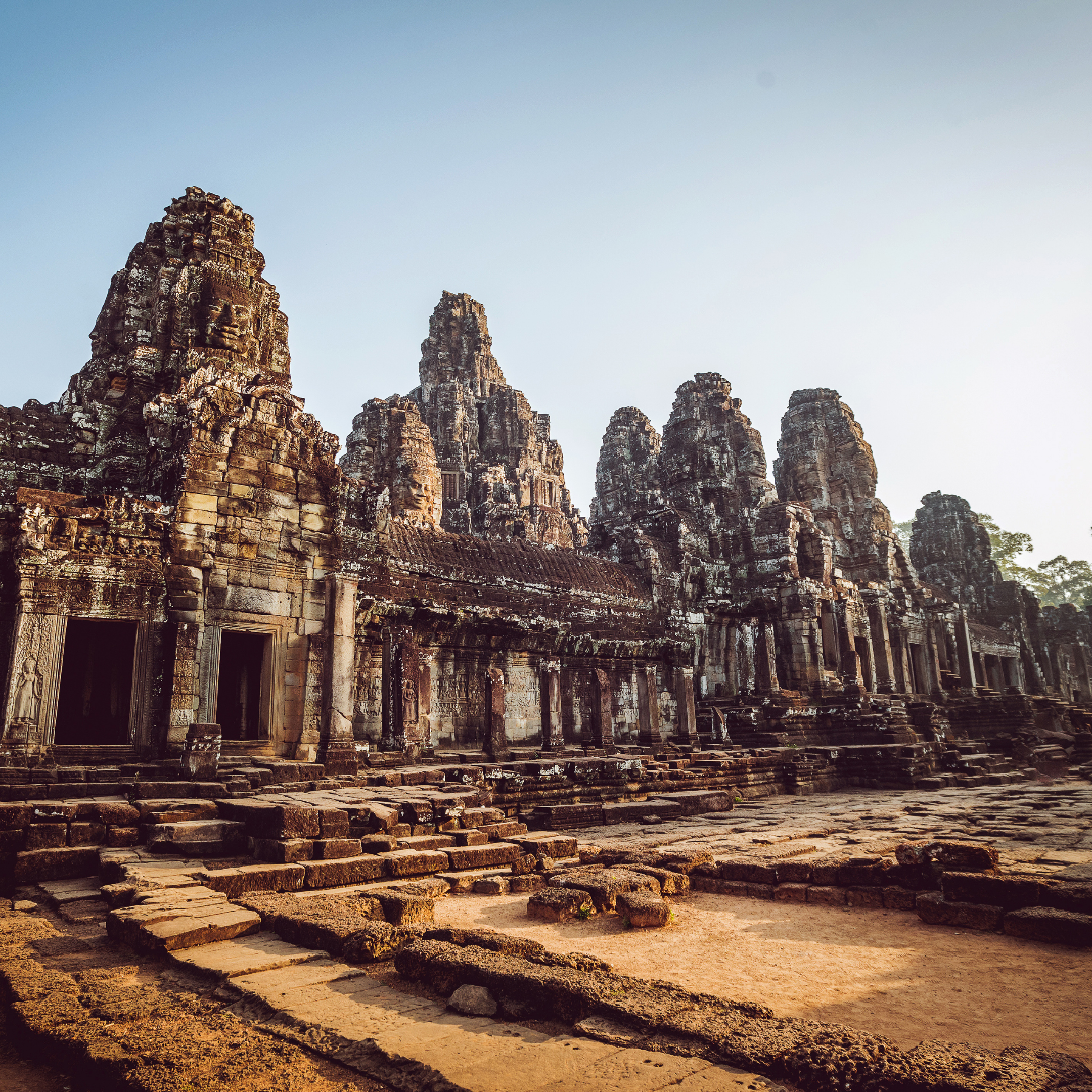 Ancient temple ruins with stone towers and intricate carvings under clear sky.