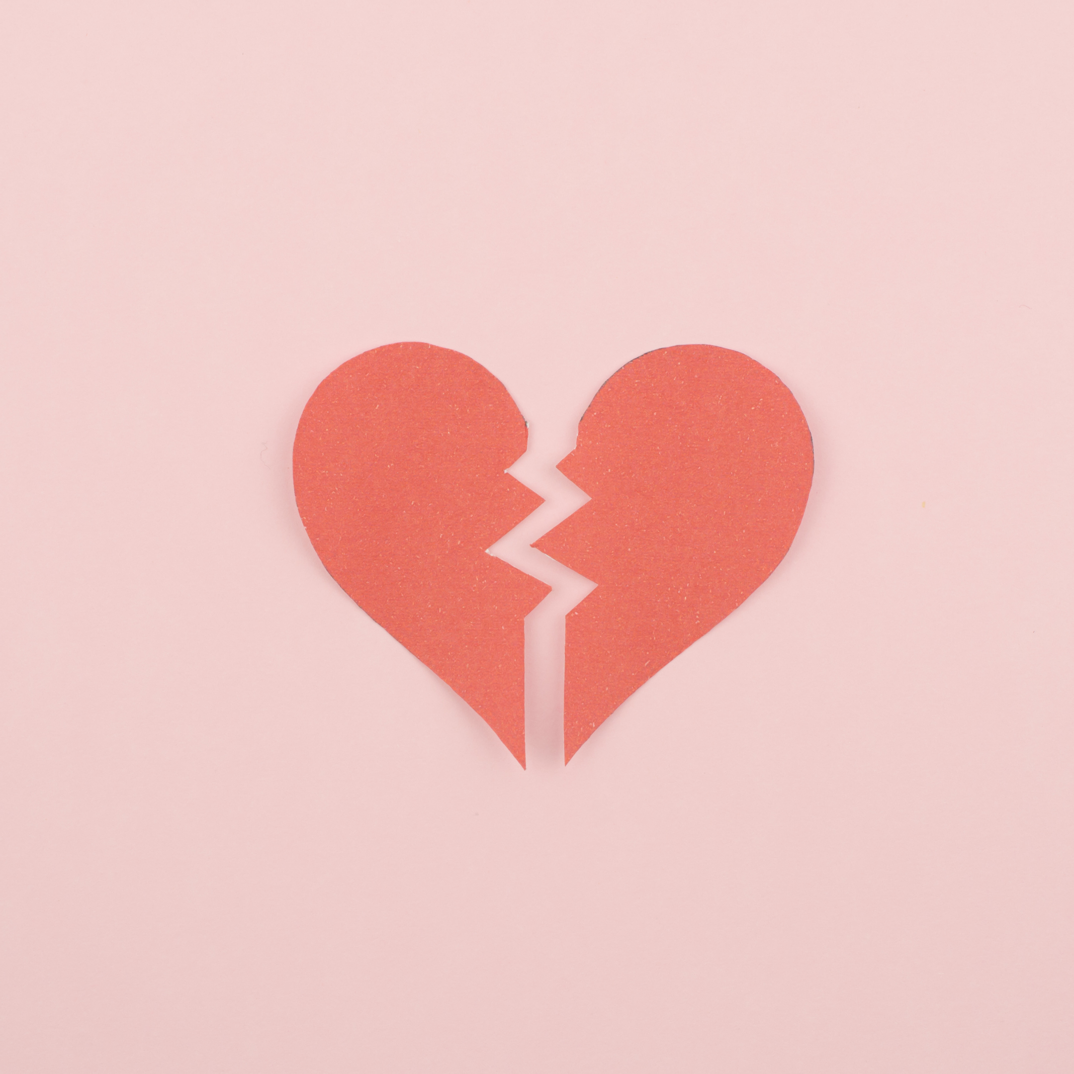 Red broken heart cutout on light pink background