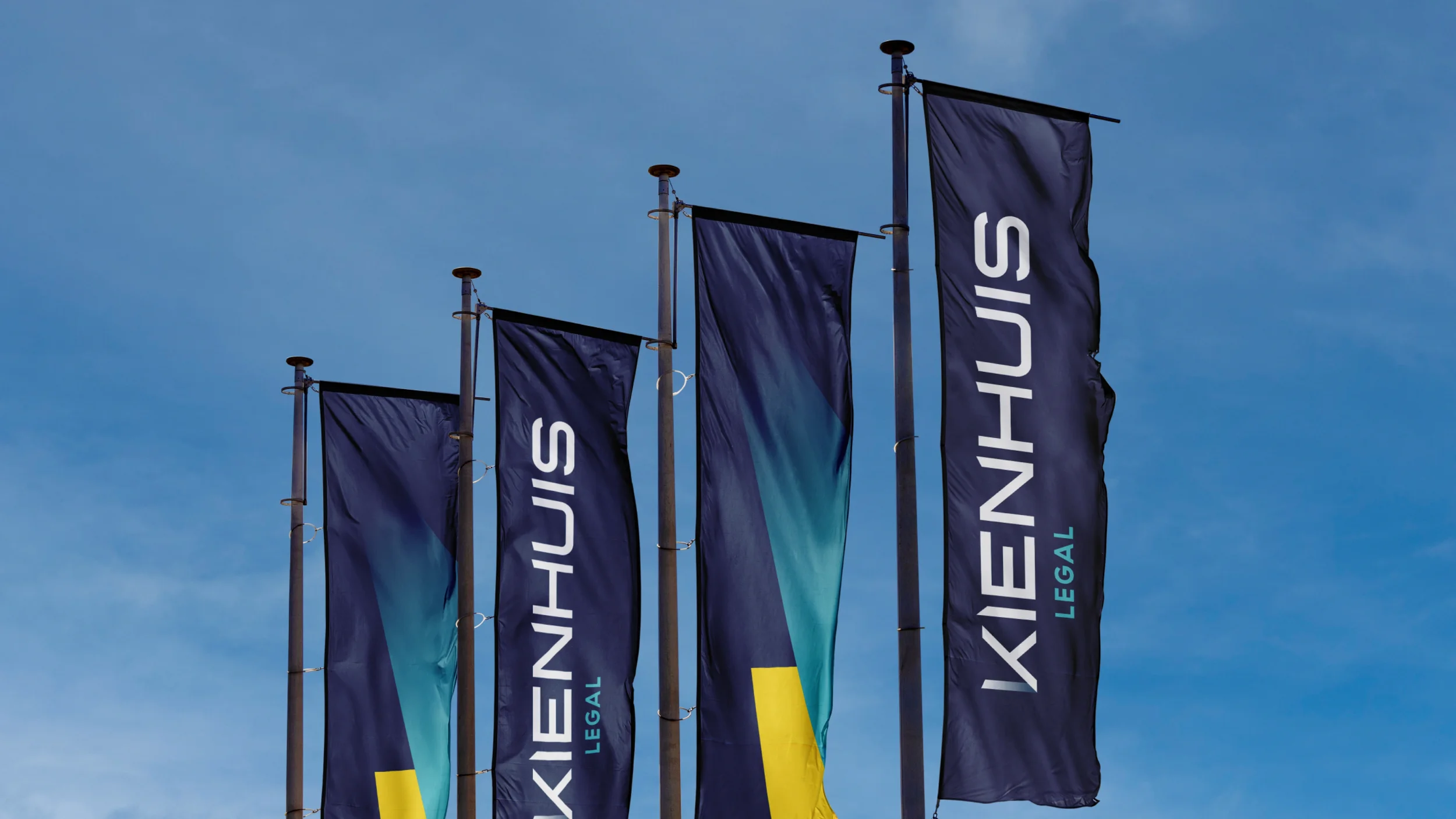 Vier vlaggen op een rij met Kienhuis Legal logo