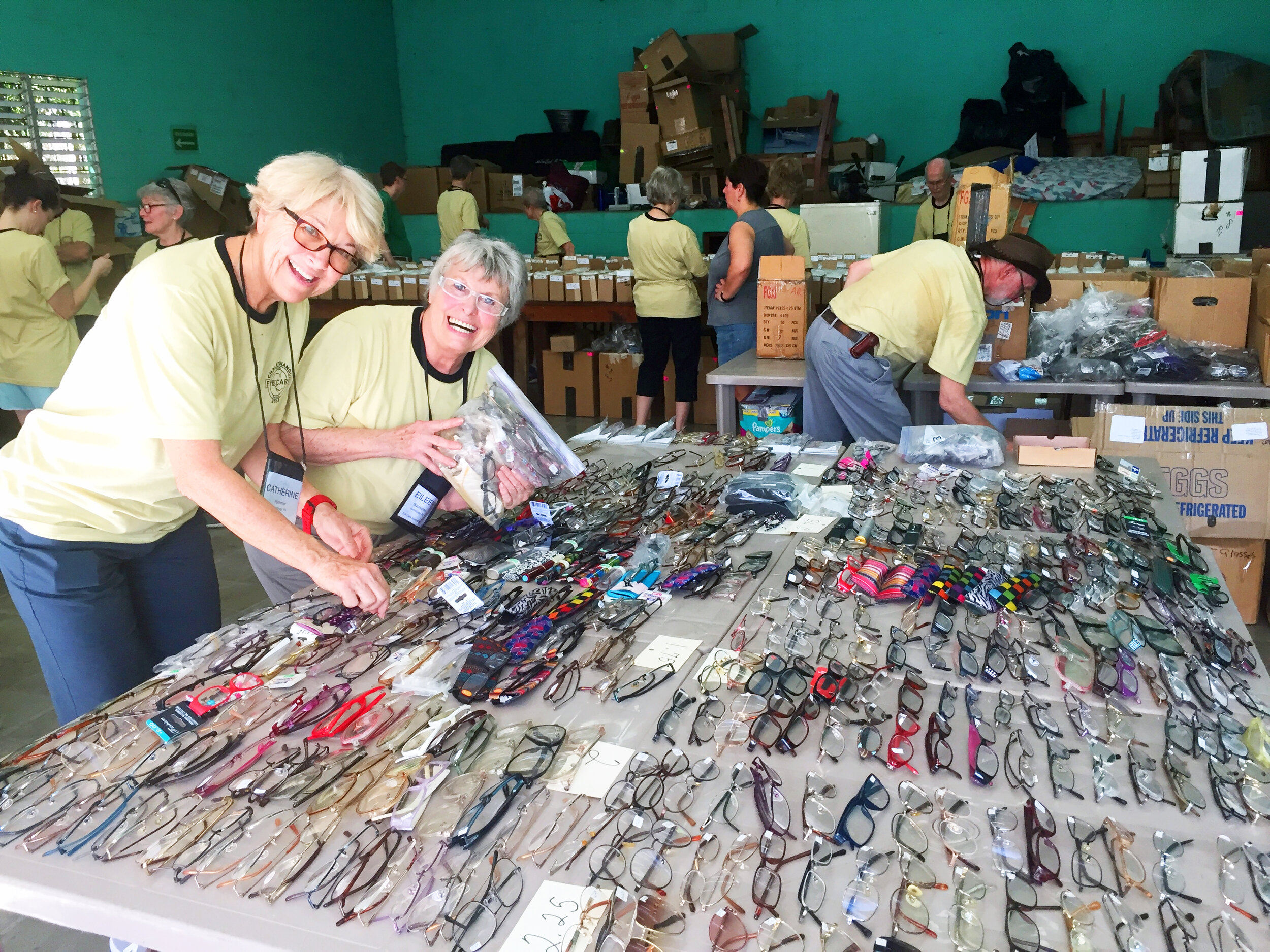 Cathy and Eileen sort through the reading glasses.