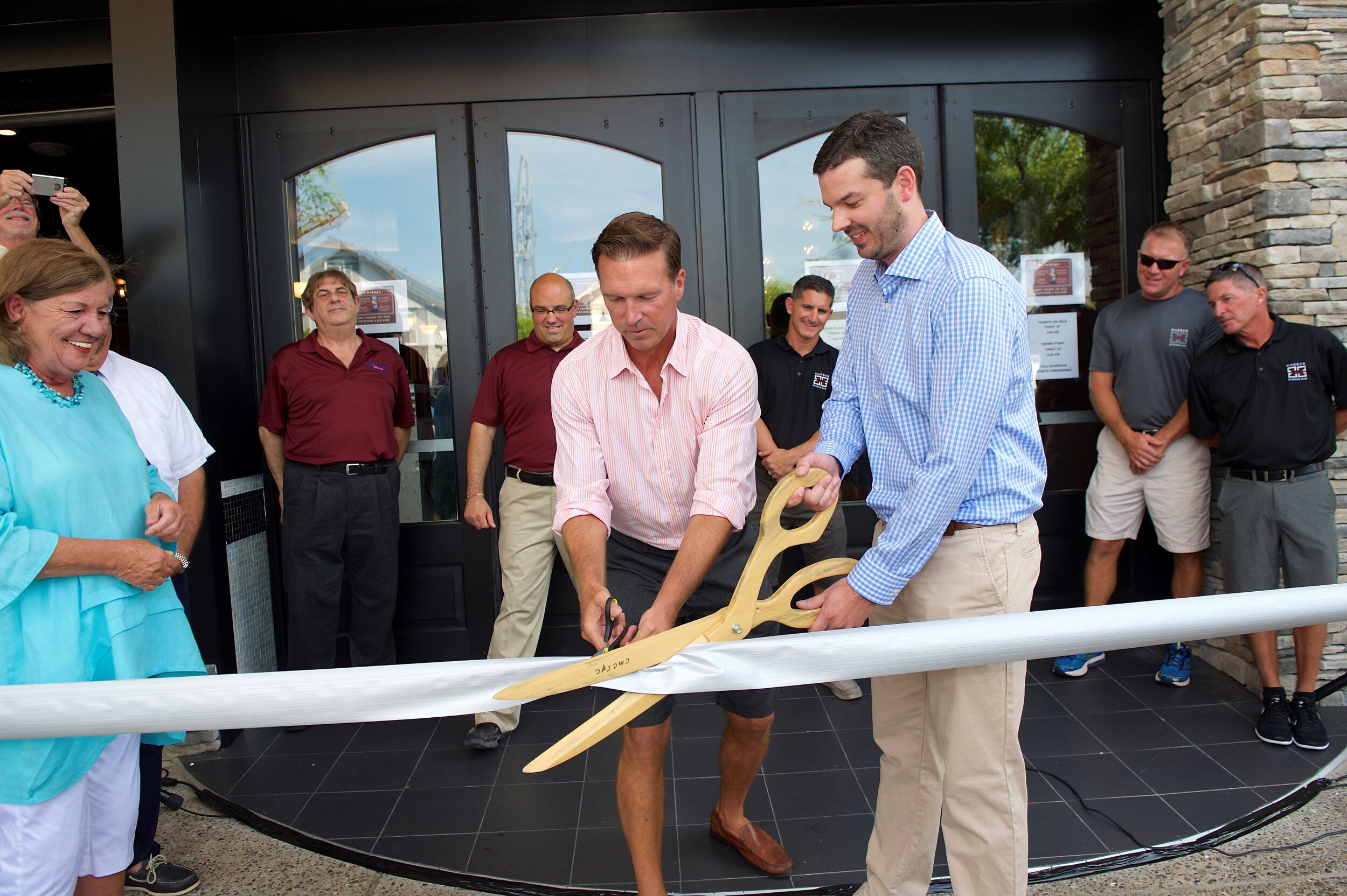 Clint Bunting (left) helps cut the ribbon during the Harbor Square Theatre opening in 2016.
