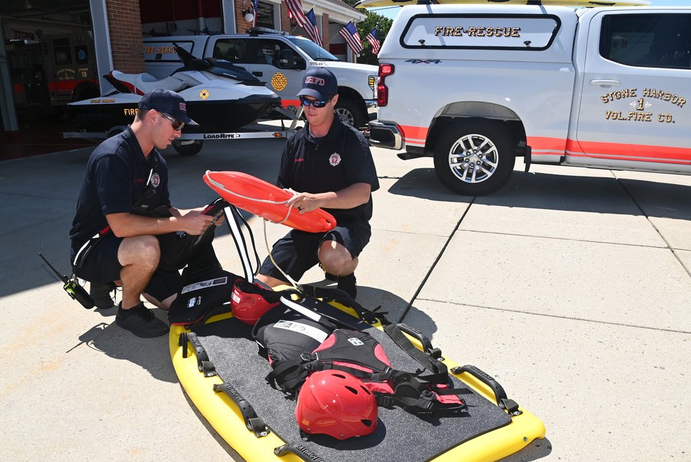 Firefighters Eric Staeger (left) and Liam Mason look over some of Stone Harbor’s water-rescue gear. The fire company responds to ocean and bay rescues, as well as when storms flood areas of town.