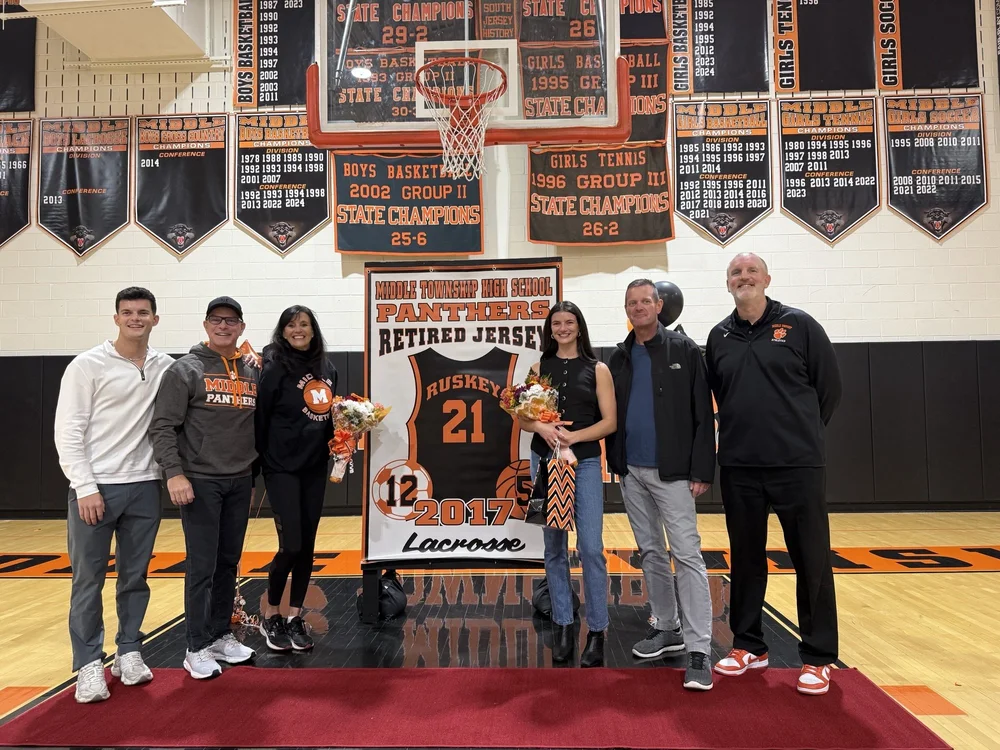 Bridget’s family – Jake, John, and Beth Ruskey  – and to the right of Bridget, her former coaches, Bob Wishart (soccer), and John Leahy (basketball).