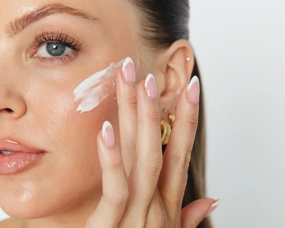 A woman applying skincare cream to her cheek