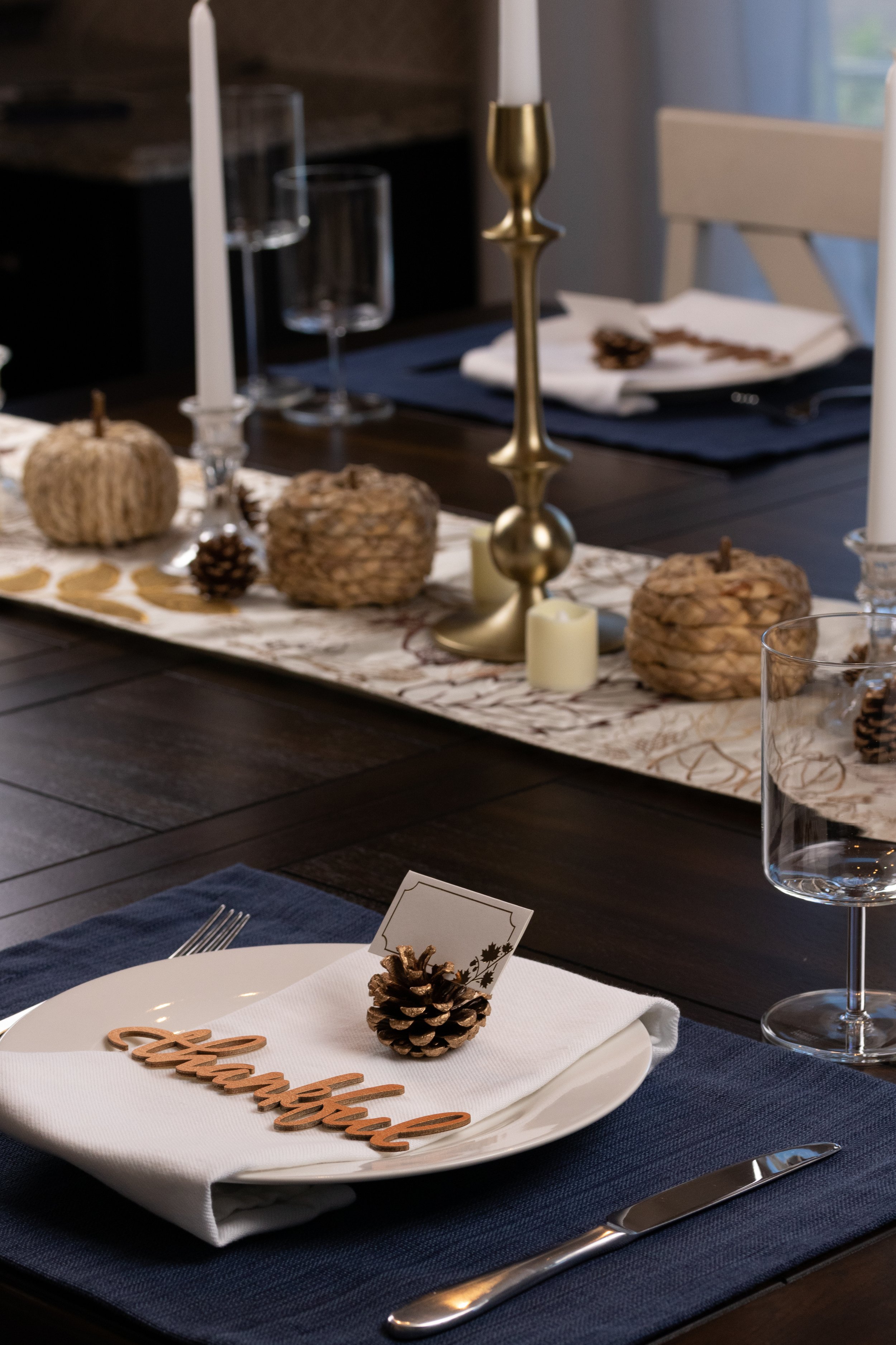 fall tablescape including a farmhouse dining table, rattan pumpkins, sparkly pine cones and battery candles
