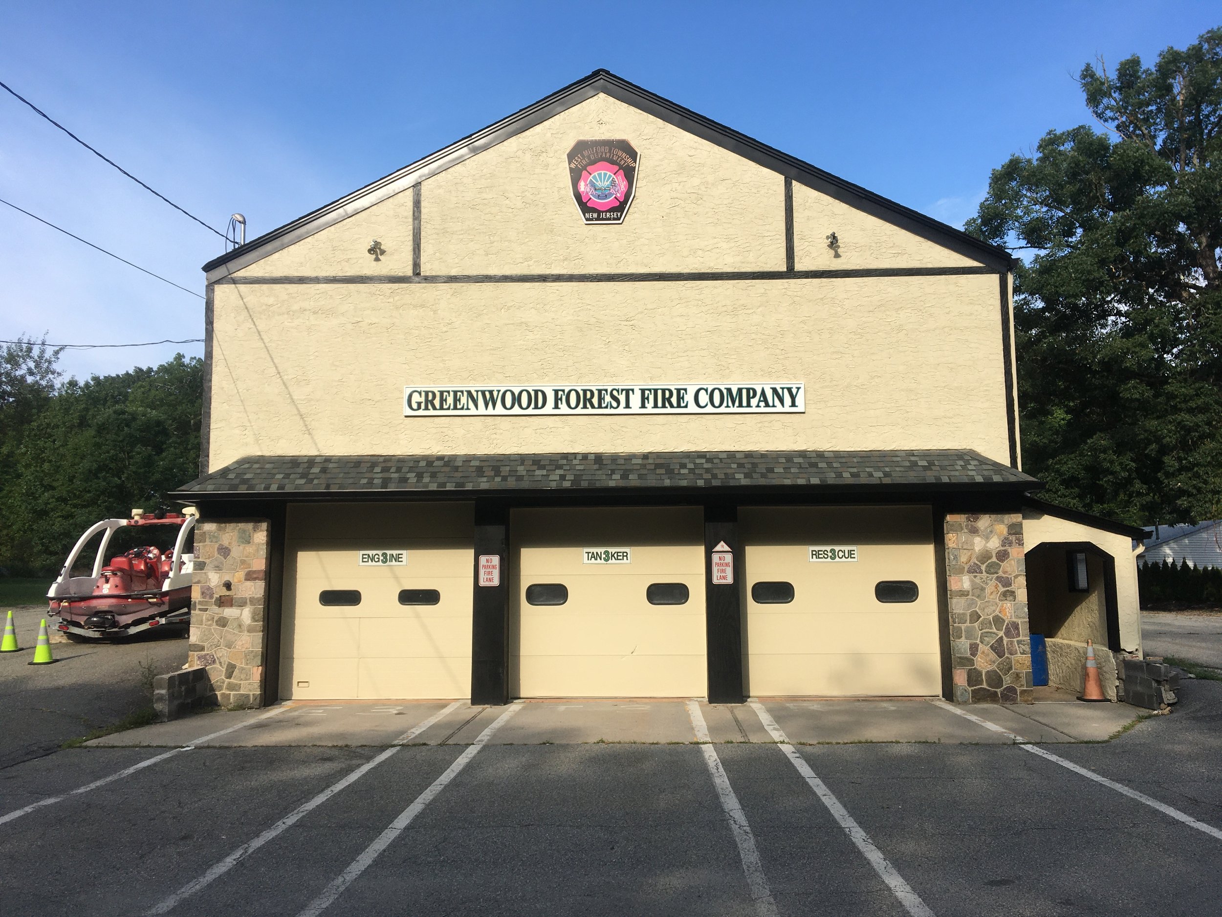 Fire station building with three garage doors, labeled engine, tanker, and rescue, and a sign reading 'Greenwood Forest Fire Company'.
