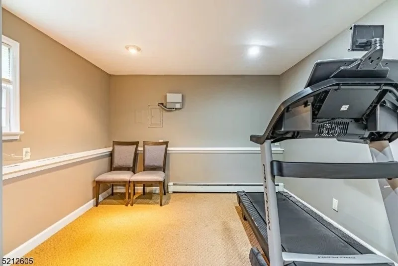 Empty room with two chairs, a treadmill, and minimal wall decor.