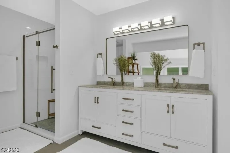 Modern bathroom with a double vanity, large mirror, and a glass-enclosed shower with sliding door.