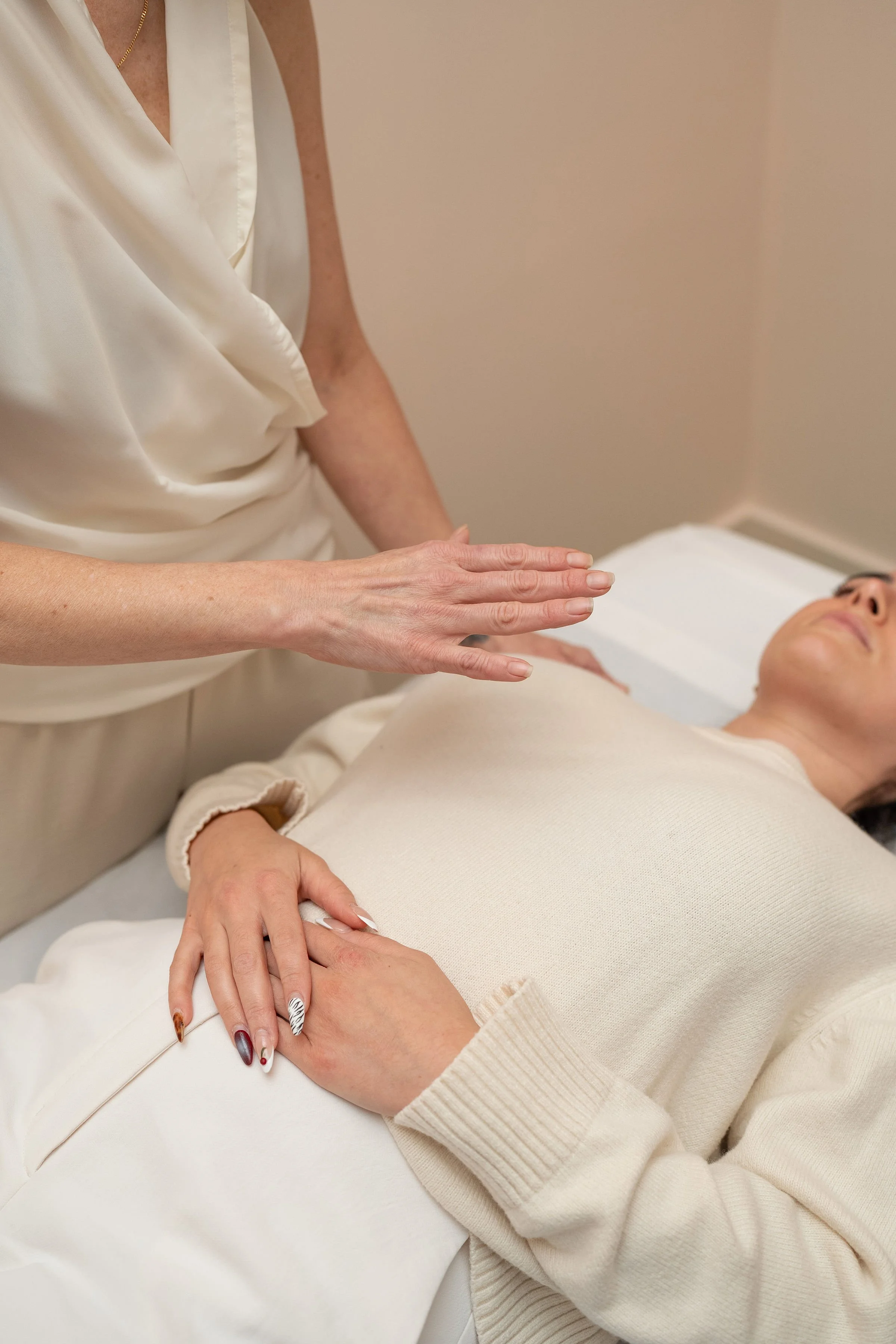 A woman lying on a medical bed, receiving a treatment or examination from a healthcare professional.