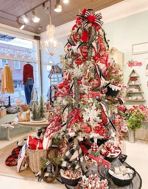 Decorated Christmas tree with red, white, and black ribbons, ornaments, and bows in a boutique storefront