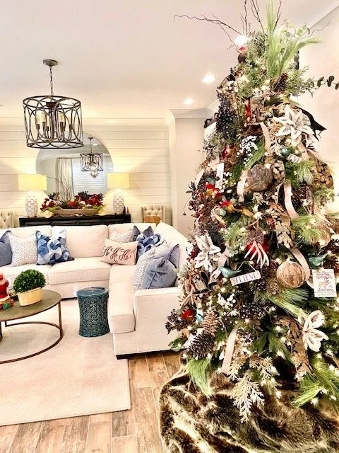 Living room with a decorated Christmas tree, white sofa with blue pillows, and modern lighting fixtures.