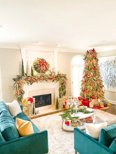 Living room decorated for Christmas with a fireplace, a decorated Christmas tree, wreath on the mantel, and presents on the floor.