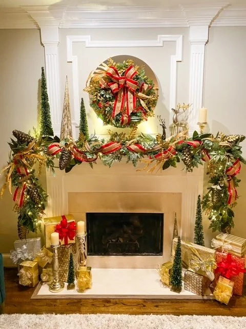 Decorated fireplace with Christmas wreath and garland, surrounded by wrapped presents and candles.