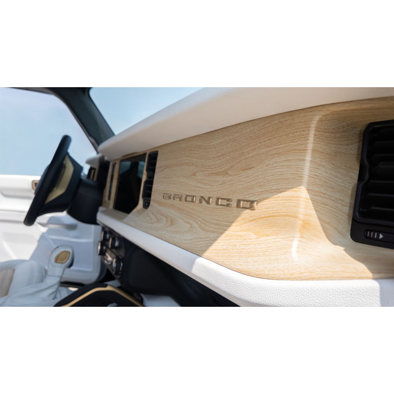 Close-up of a vehicle interior dashboard with a wooden panel and the word 'Bronco' logo.