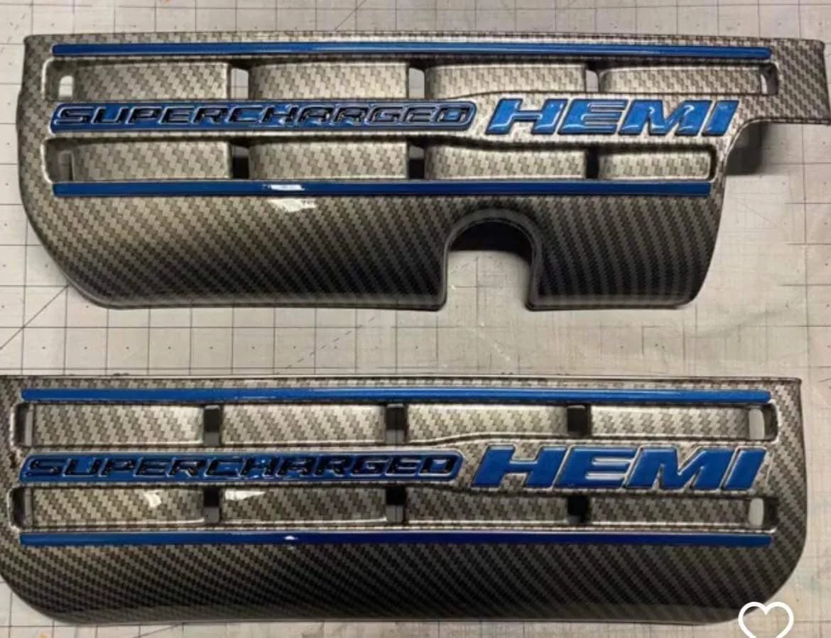 Carbon fiber car grille with blue lettering that says "Supercharged HEMI".