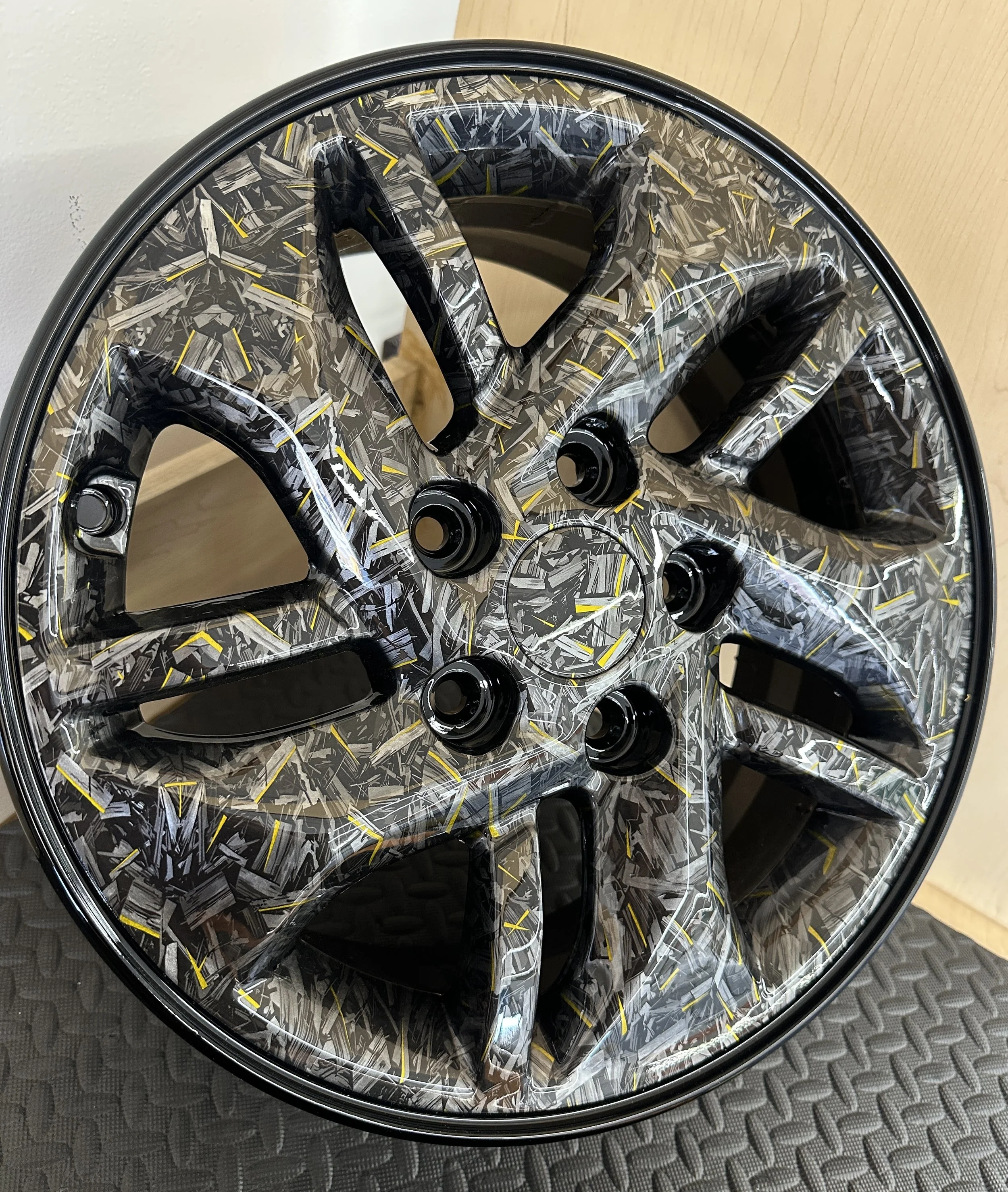 Car wheel with a black, silver, and yellow camouflage pattern.