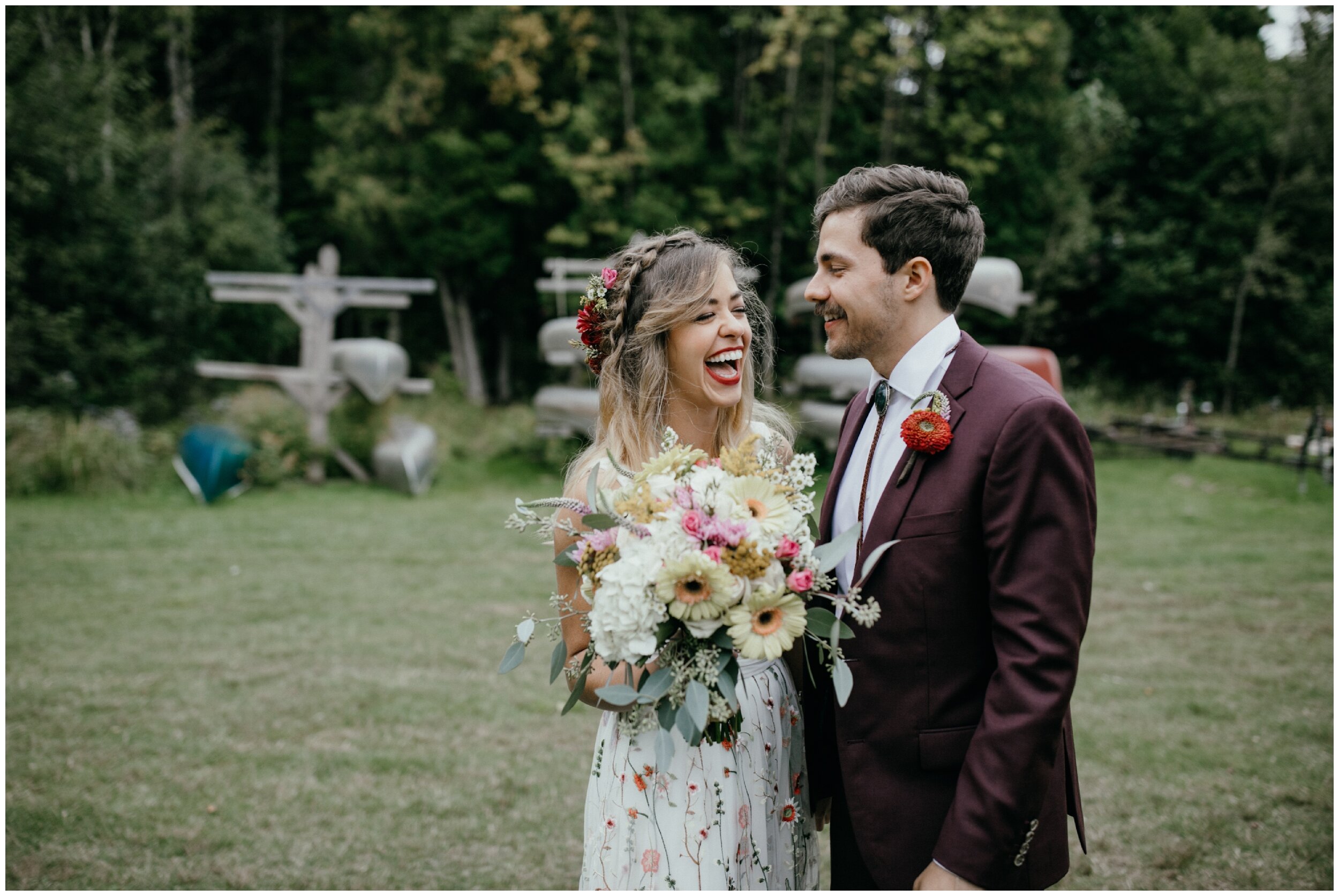 Bride and groom laughing during whimsical Minnesota summer camp wedding in the woods