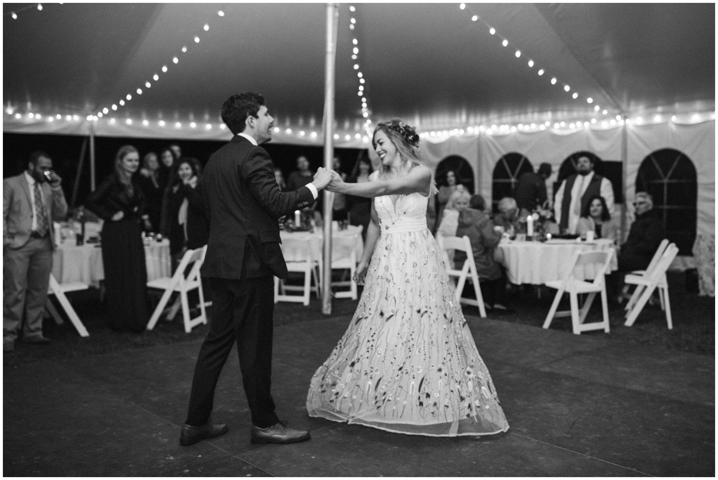 Bride and groom dancing under bistro lights during Minnesota summer camp tented wedding reception
