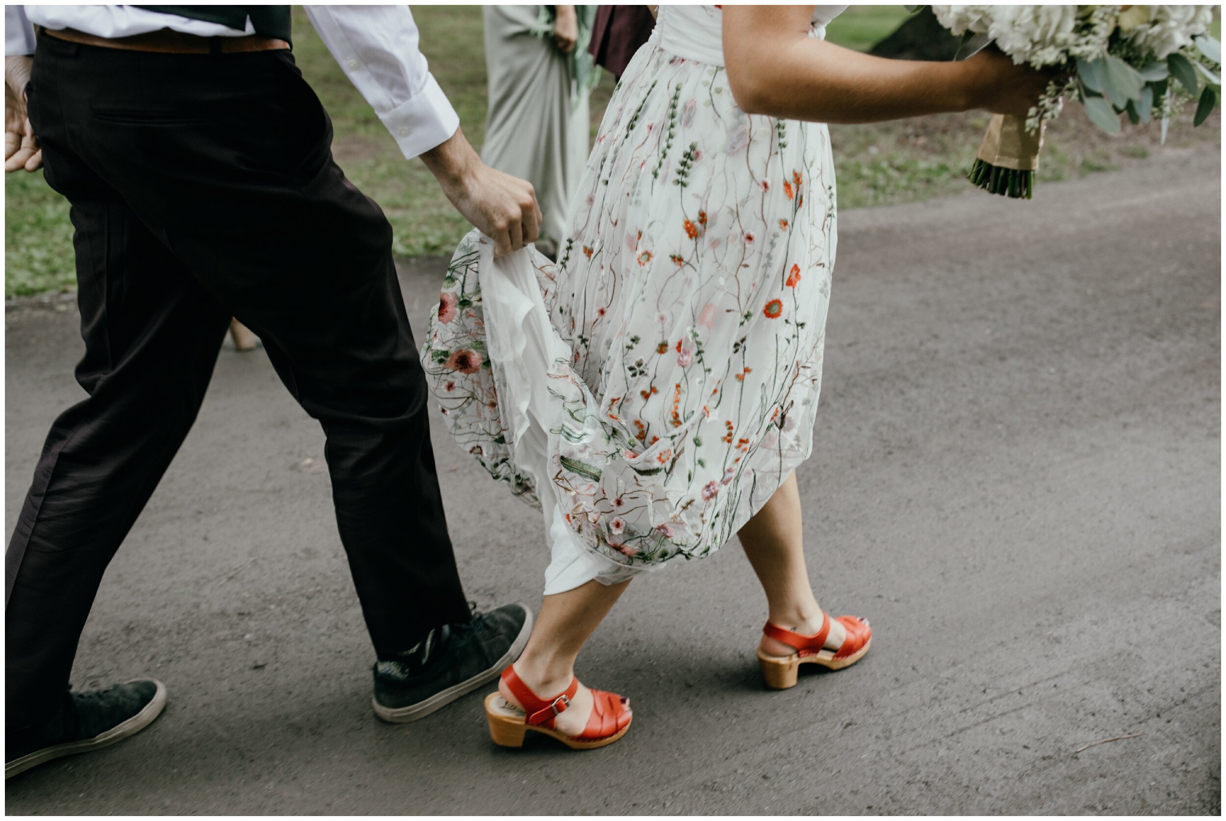Bride wearing floral print wedding dress and red clogs for Minnesota Summer camp wedding