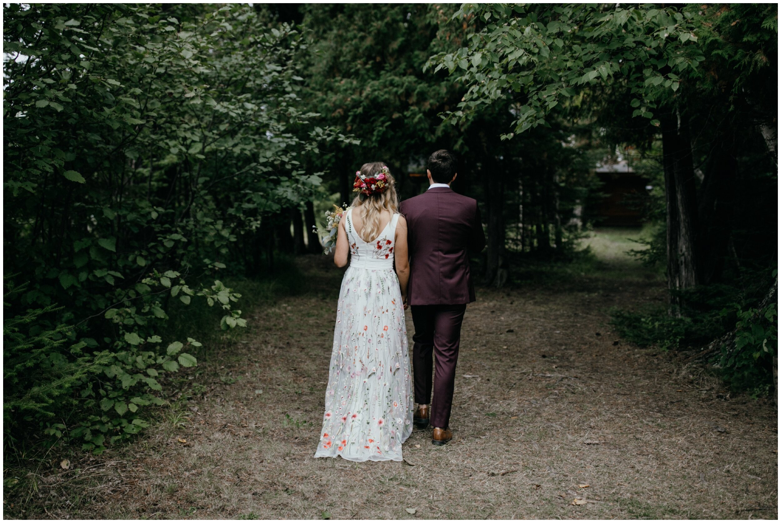 Bride and groom walking together after Minnesota summer camp wedding in the woods