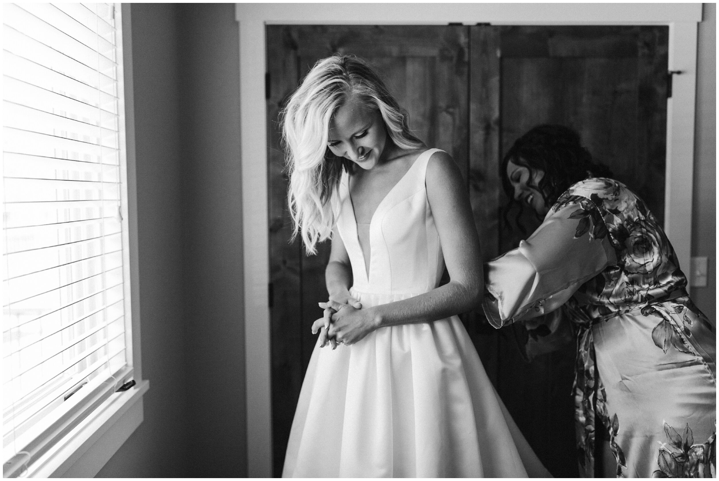 Bride's sister helping her into her wedding dress at Grand View Lodge