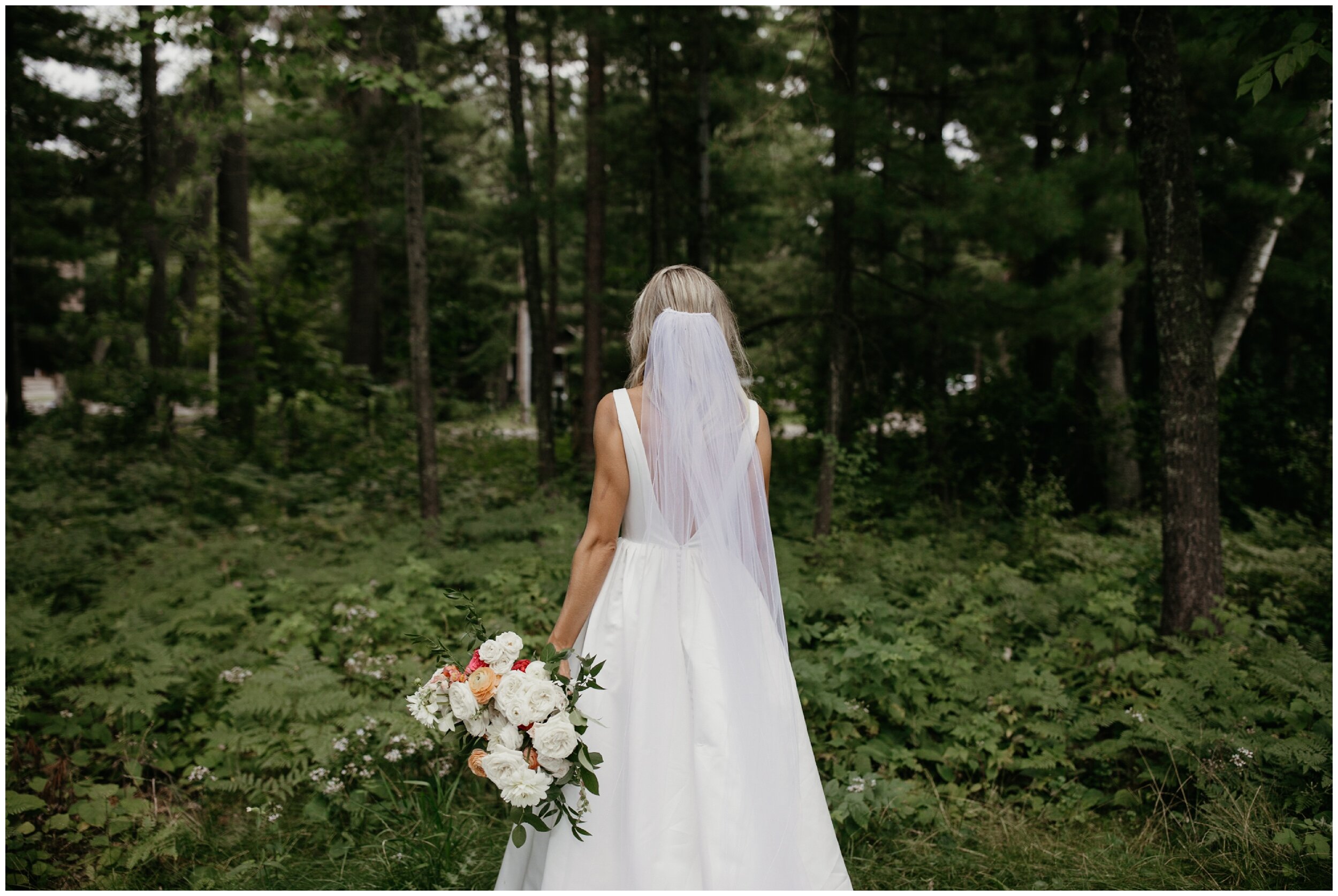 Bride standing in woods at Grand View lodge summer wedding 