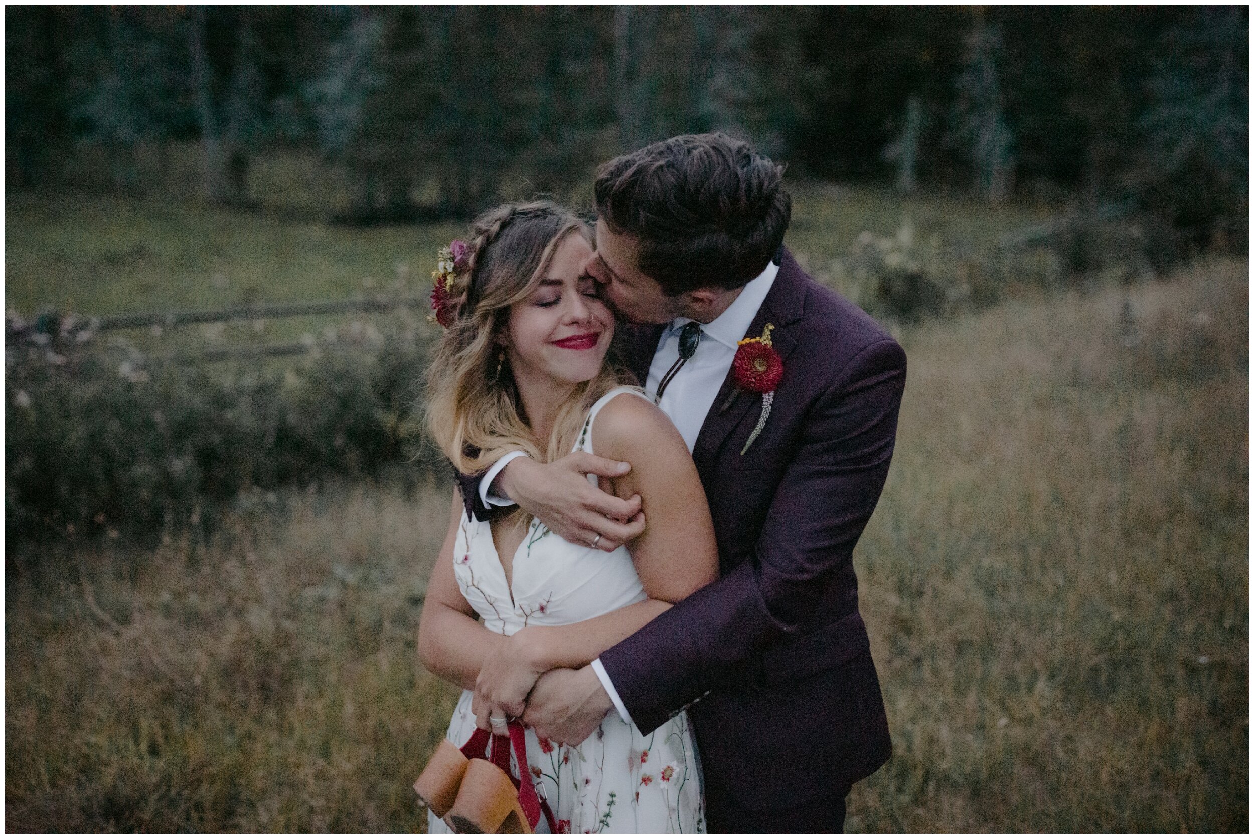 Groom kissing bride's forehead during Minnesota summer camp wedding