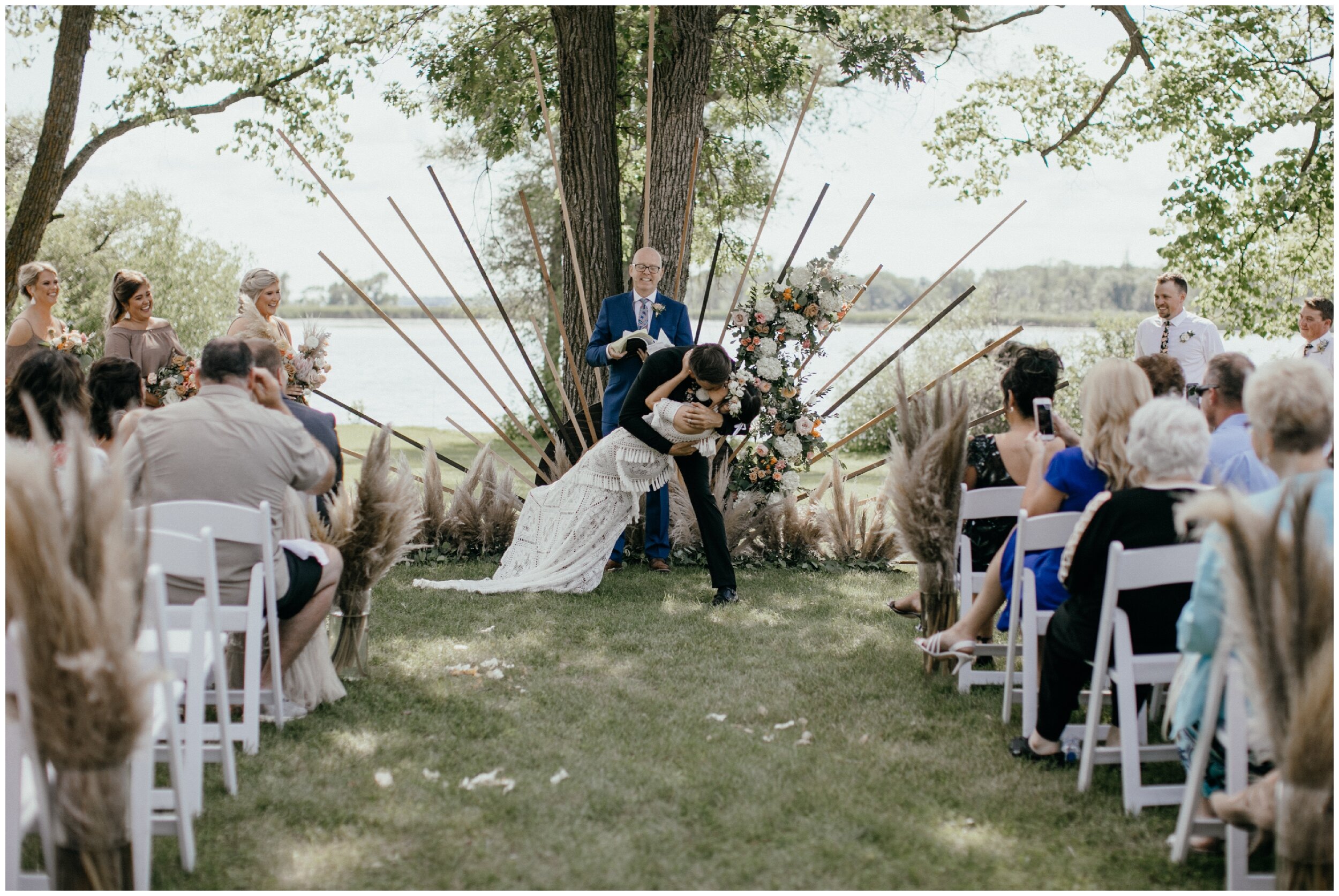 Bride and groom kiss during modern boho wedding ceremony at private lakeside estate in northern Minnesota