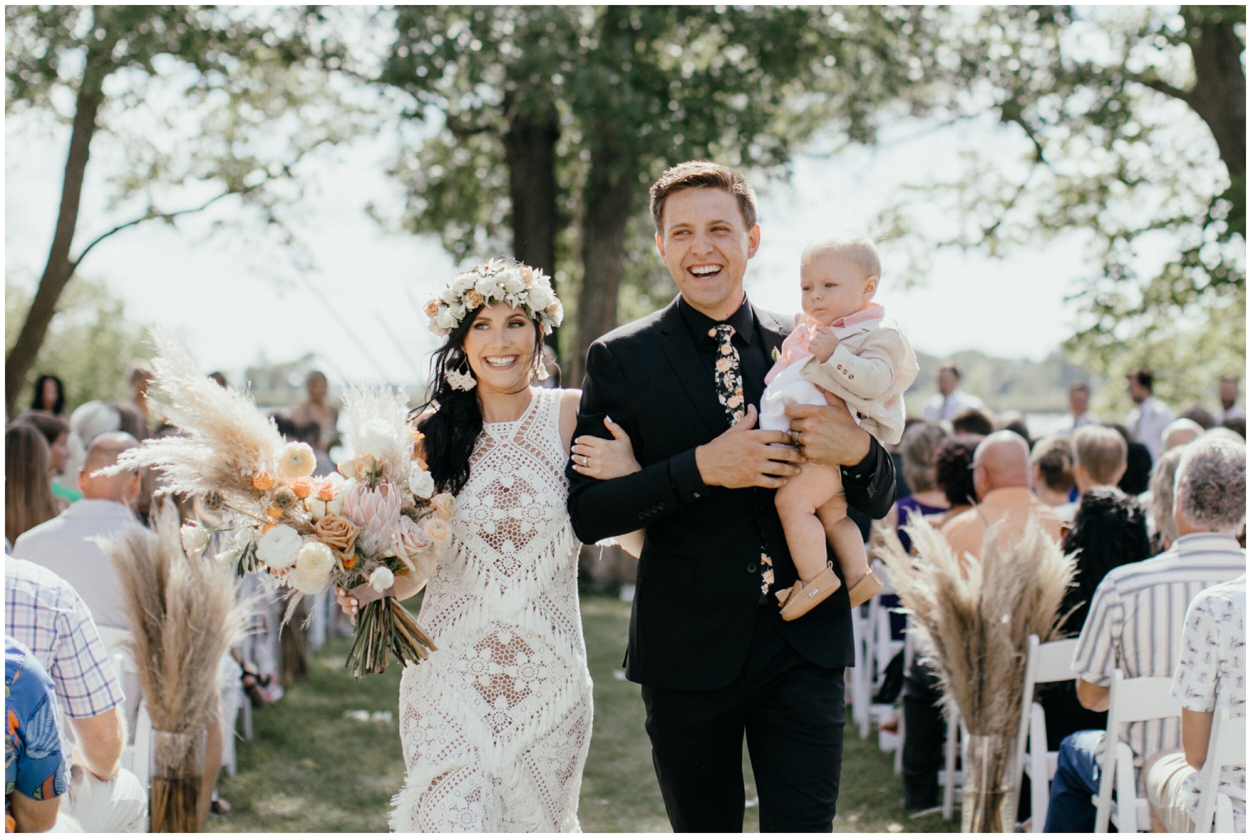 Bride and groom walking down aisle with their baby at Minnesota backyard wedding