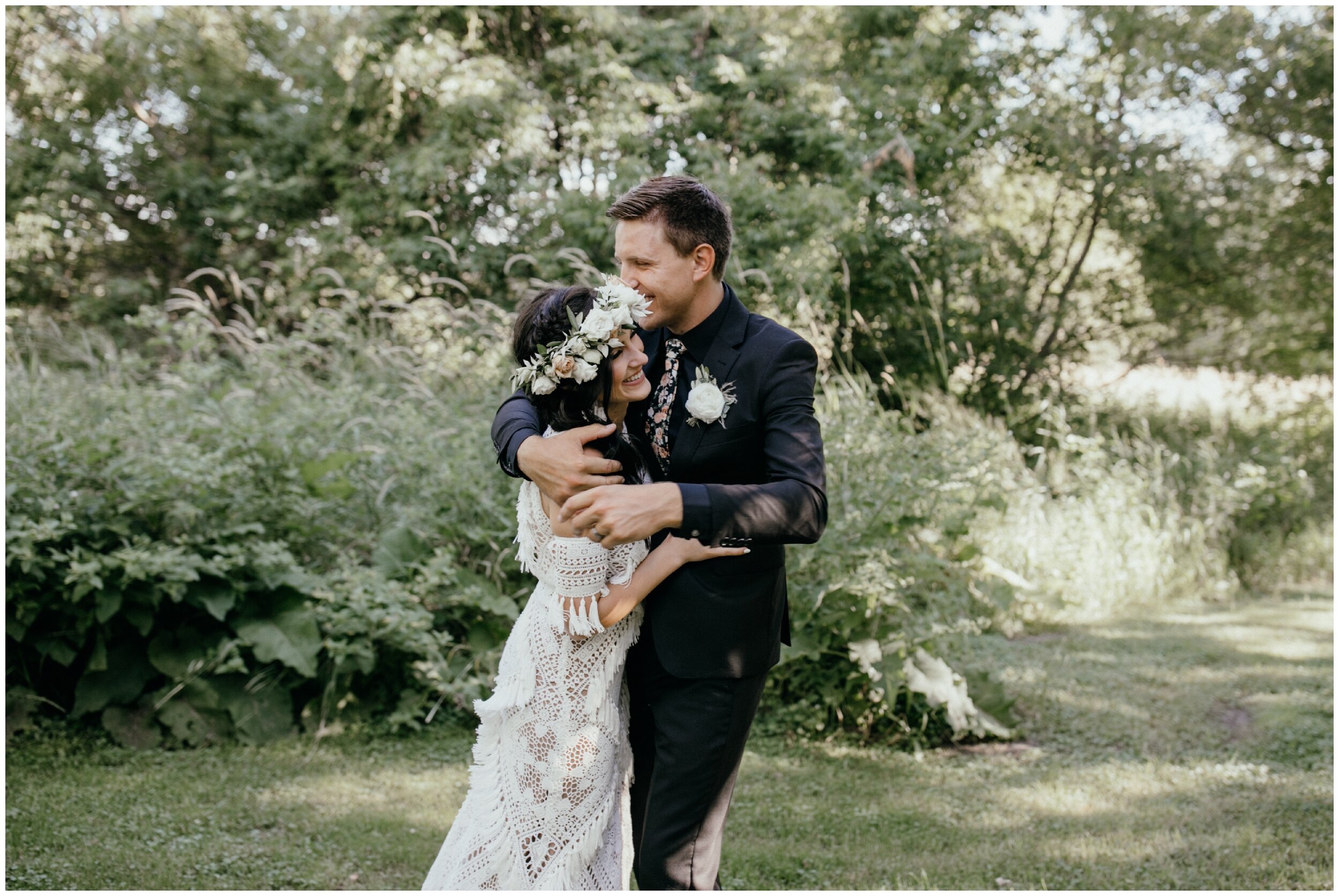 Bride and groom laughing with arms wrapped around each other during backyard Minnesota summer wedding