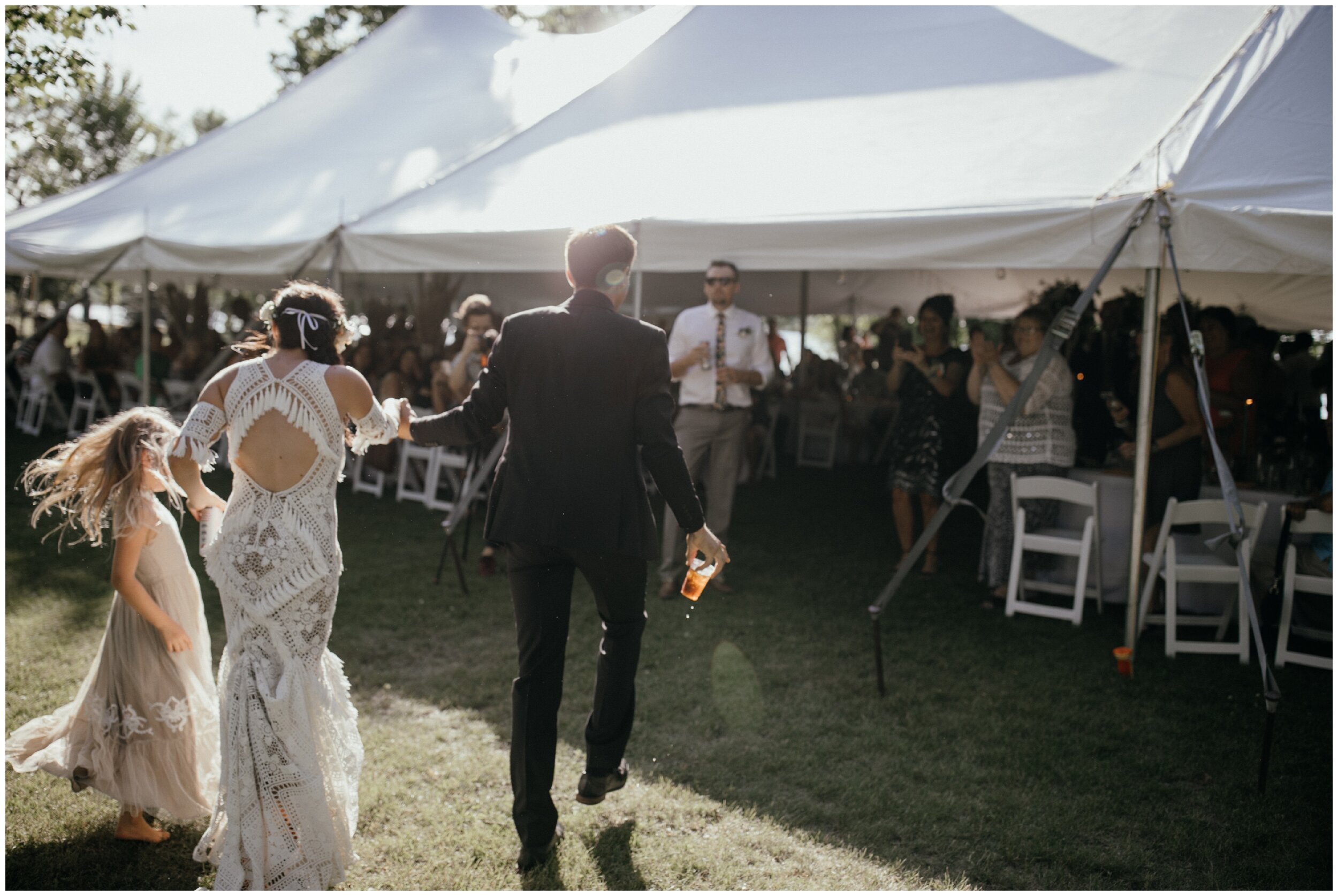 Bride and groom walking to boho outdoor tented wedding reception in northern Minnesota