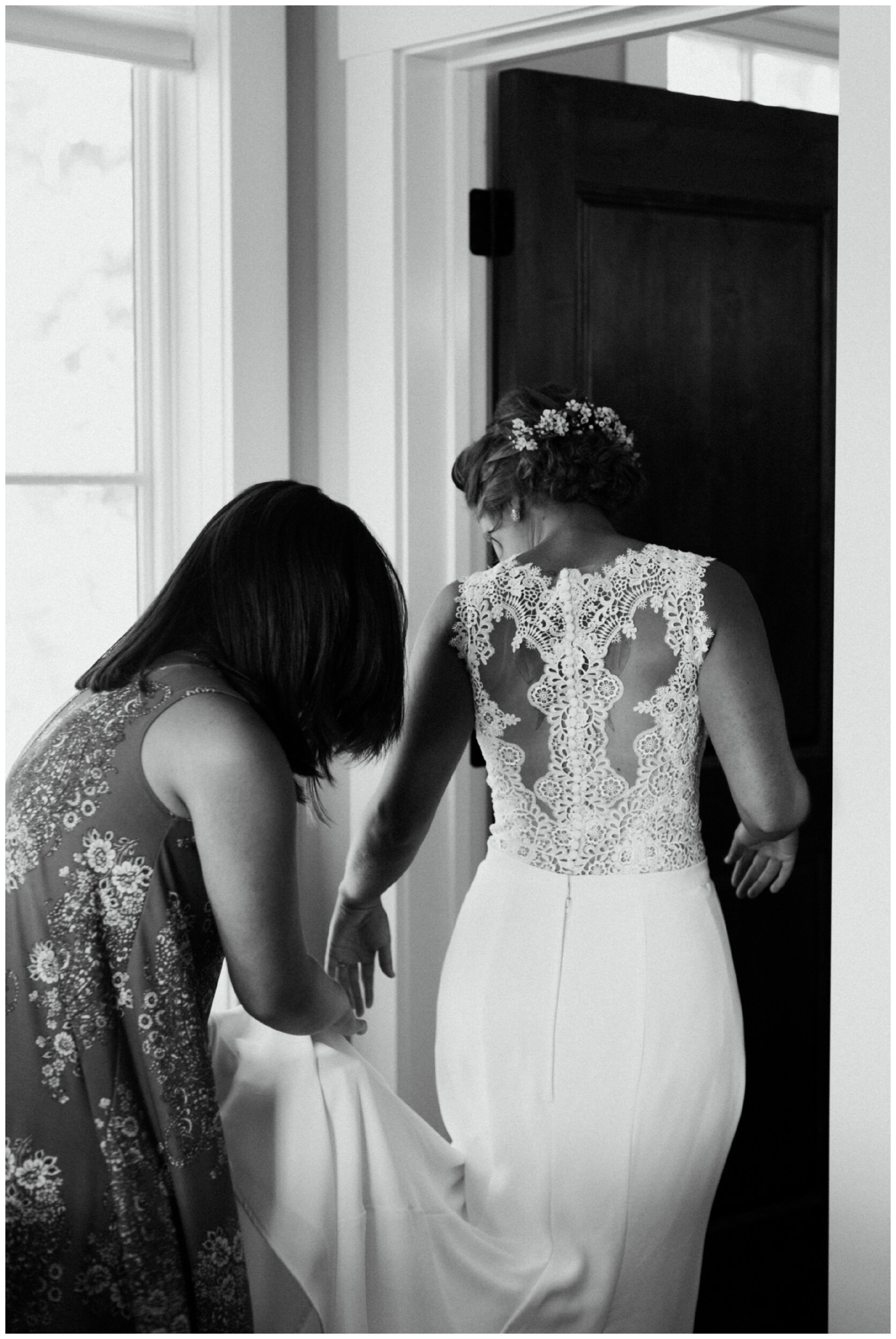 sister of the bride helping her into gorgeous lace back wedding dress for Brainerd, Minnesota lakeside wedding