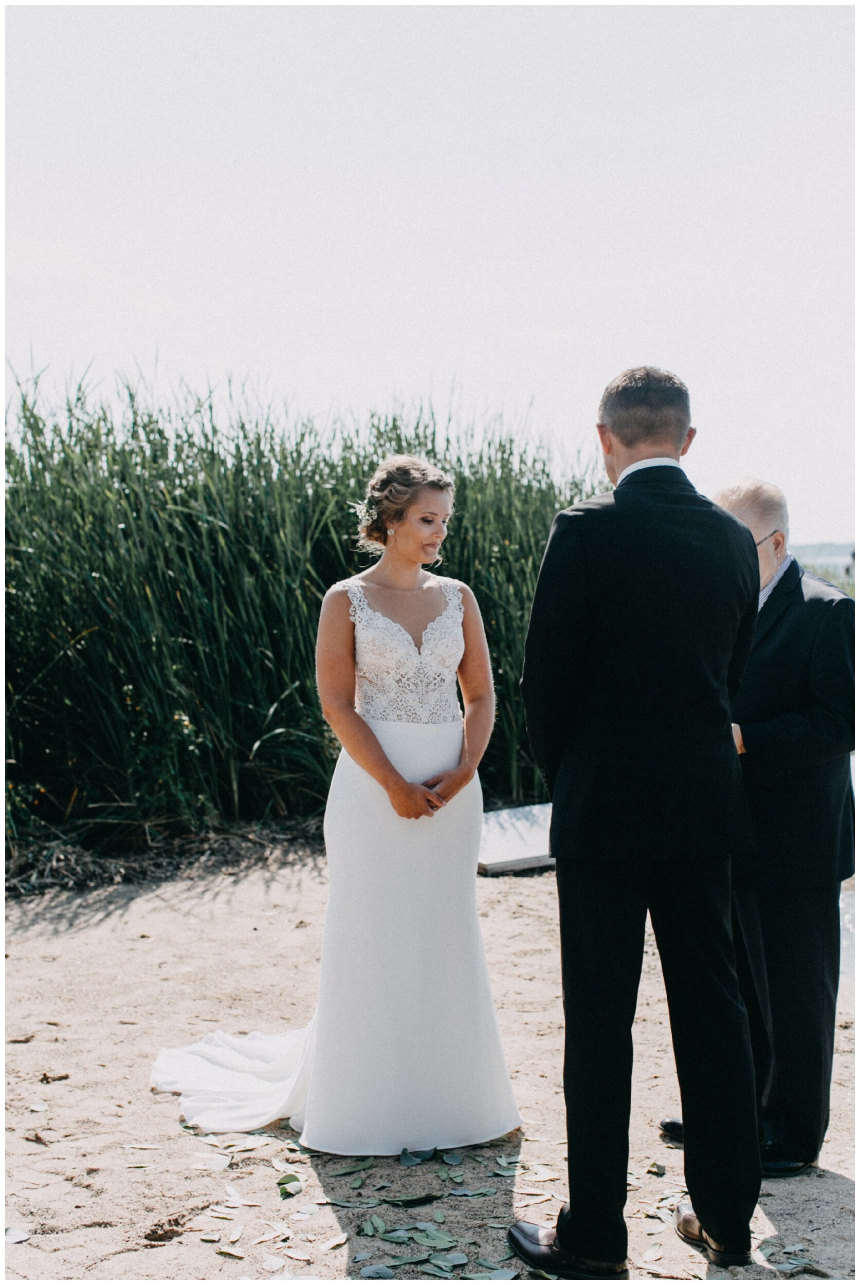 Bride and groom standing on sandy beach during lakeside wedding ceremony in Brainerd, Minnesota