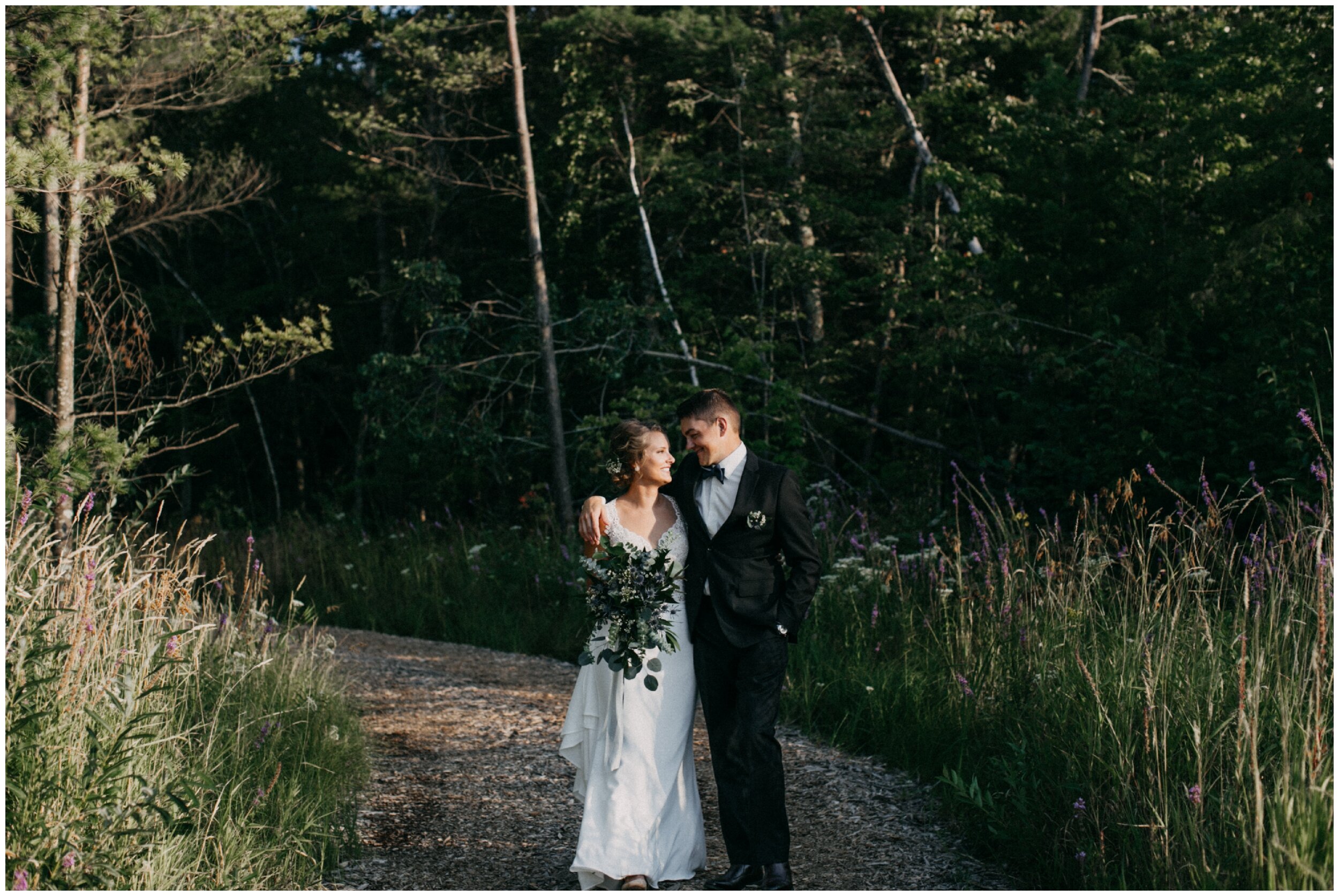 Bride and groom standing on wooded path at Brainerd, Minnesota cabin wedding