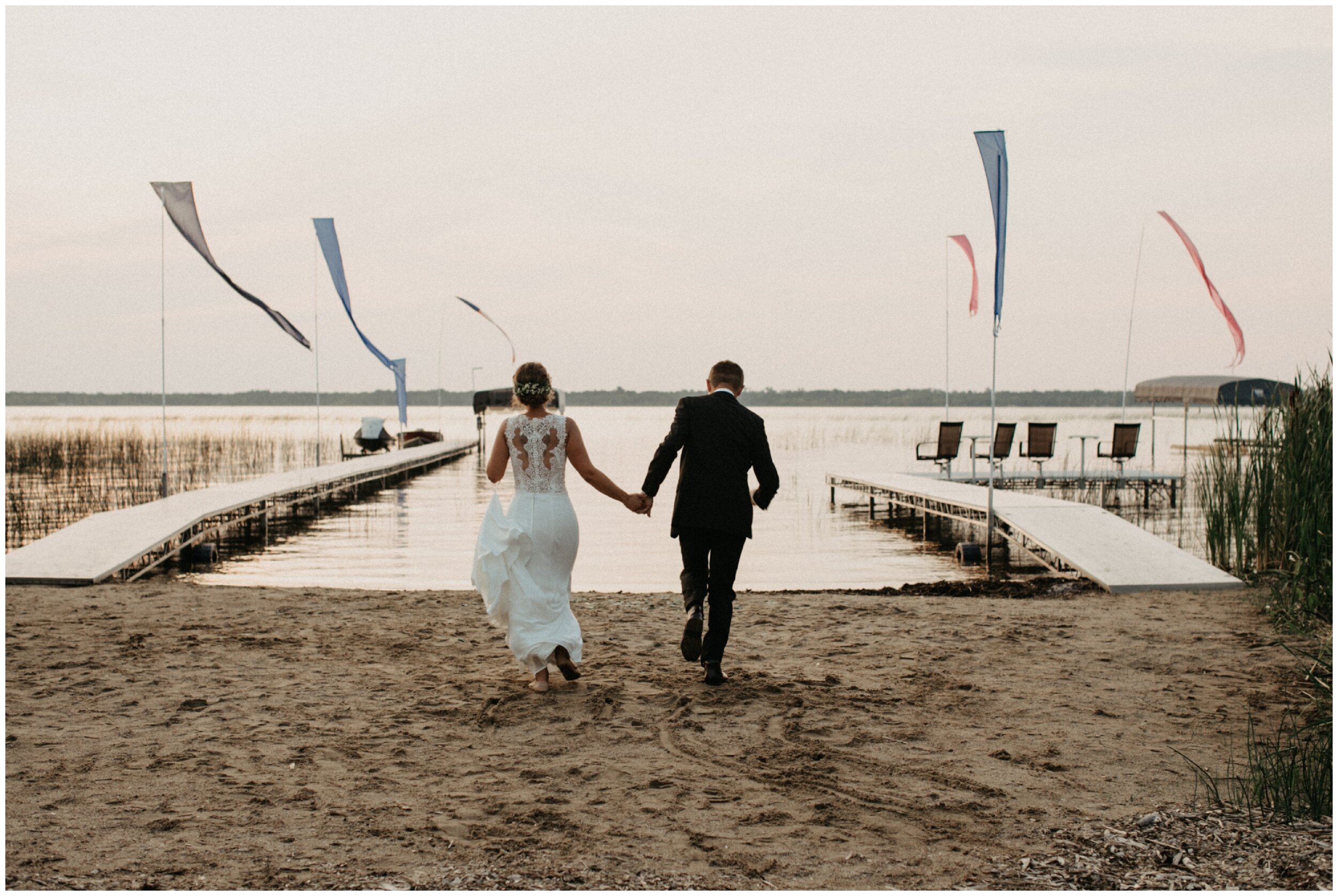 Bride and groom running on sandy beach on Lake Edward in Brainerd, Minnesota